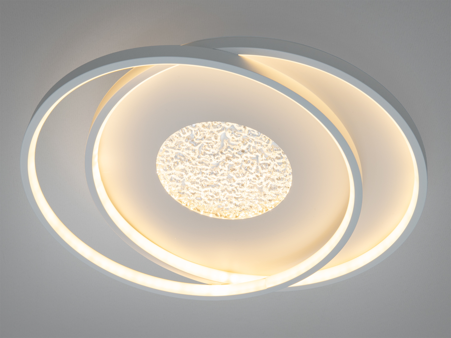 Стельовий світильник з теплим жовтим світлом, що виходить з двох пересічних кілець і текстурованого центру. Підходить для затишних просторів.