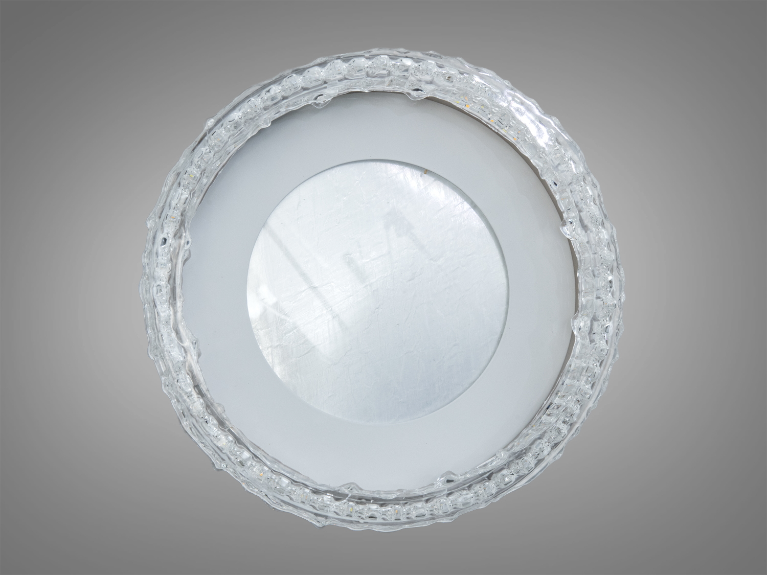 Вид зверху на стельову лампу з матовим центром і прозорим обідком, що створює ефект розсіювання світла. Підходить для офісів.