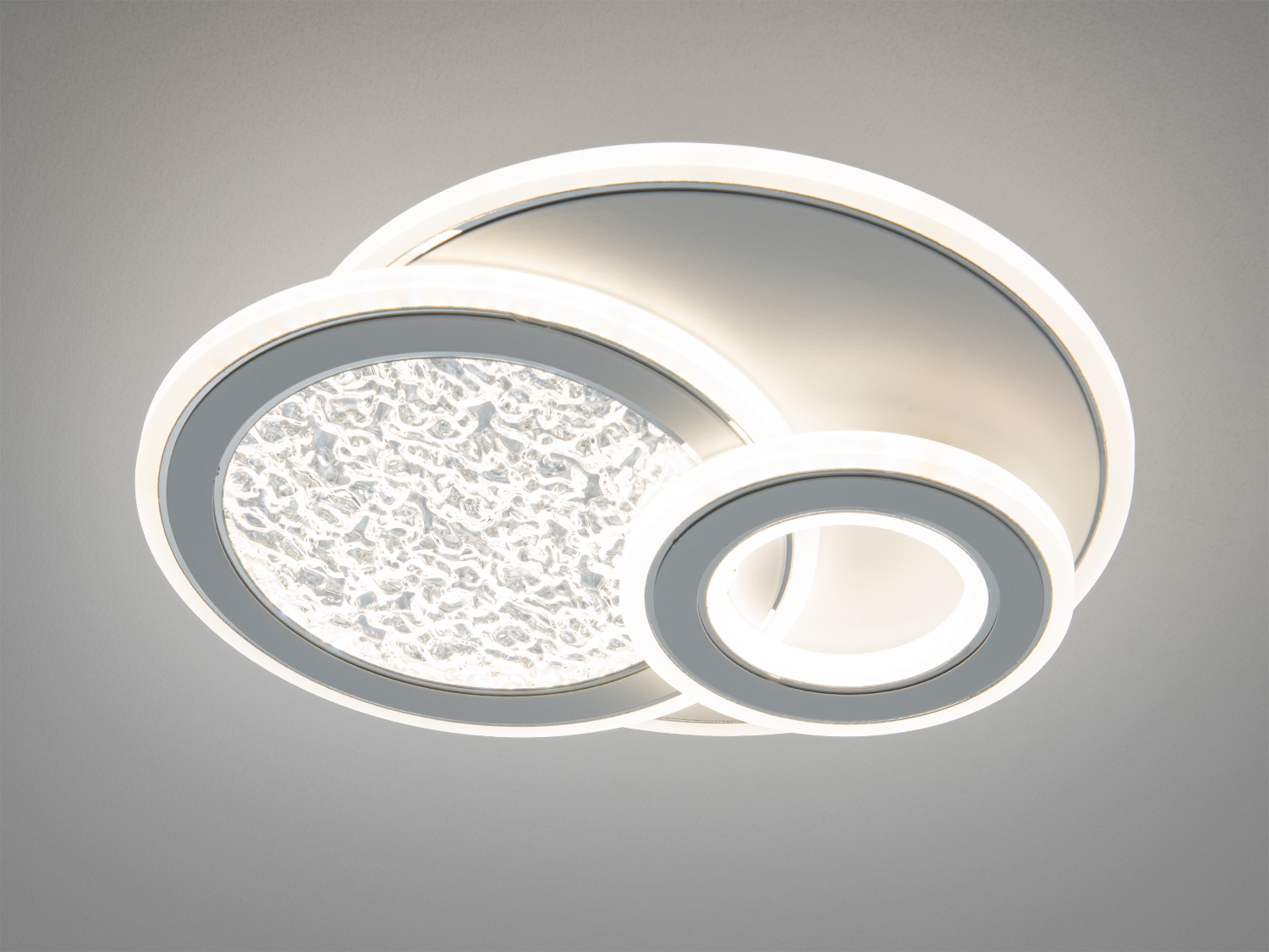 Стельовий світильник з двома кільцями, що випромінюють біле світло, має текстуровану поверхню.