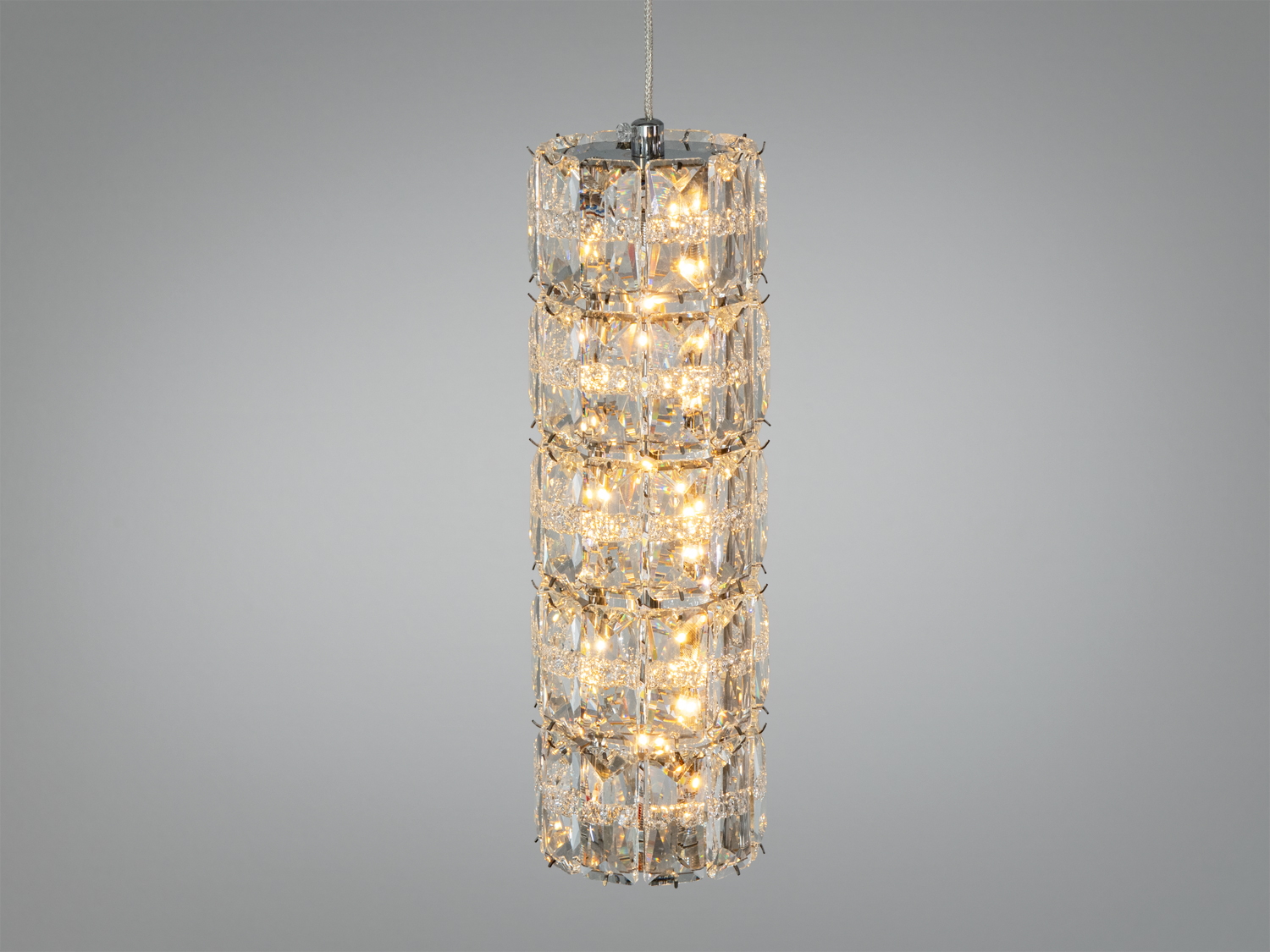 Підвісний світильник циліндричної форми з кришталевими елементами, що відбивають світло, підходить для сучасного інтер′єру.