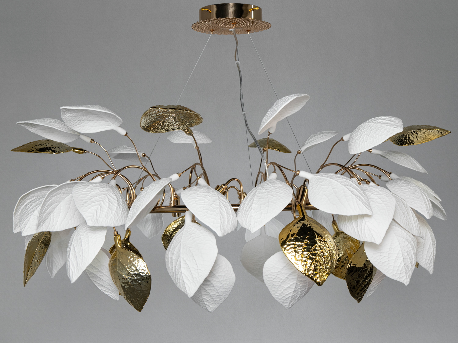 Люстра з білими та золотими листками, що нагадують дерево. Виготовлена з металу, підходить для вітальні або їдальні.