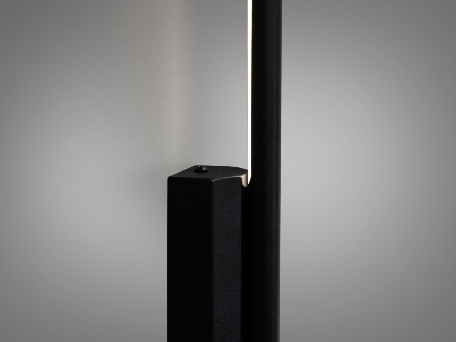 Чорний настінний світильник з довгою панеллю, що забезпечує акцентне освітлення. Використовується для декоративних цілей.