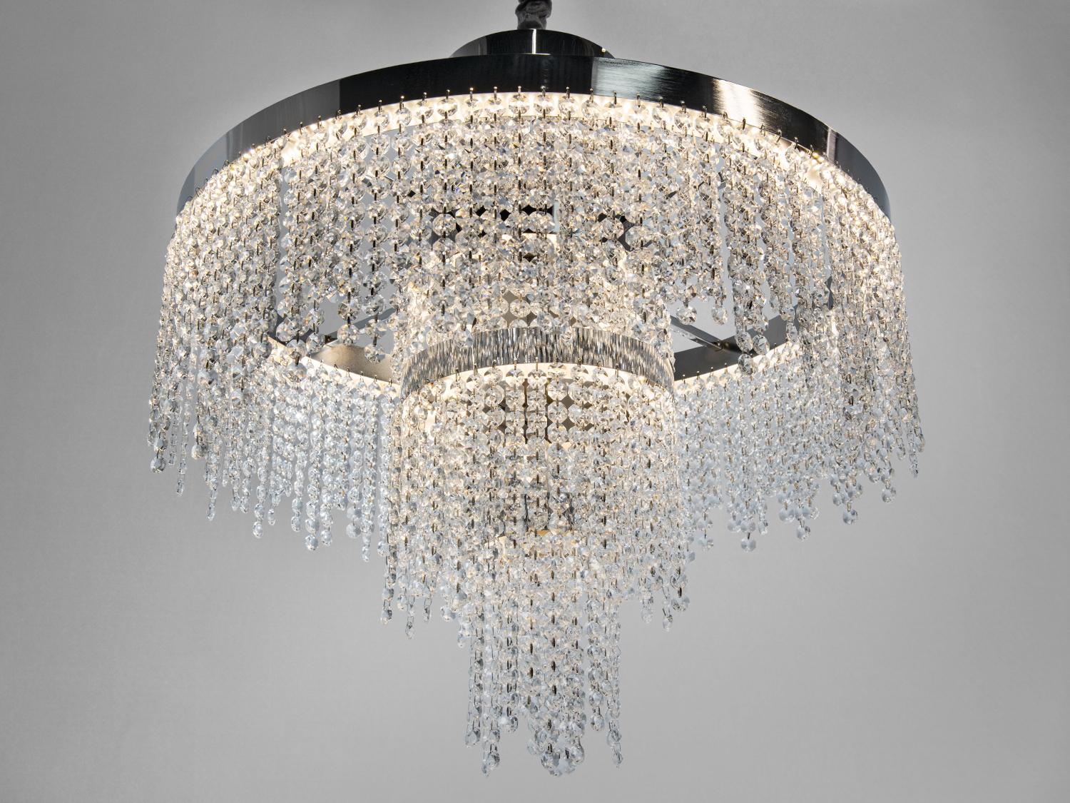 Елегантна кришталева люстра з багаторівневими підвісками. Вона забезпечує яскраве освітлення, підходить для просторих приміщень.