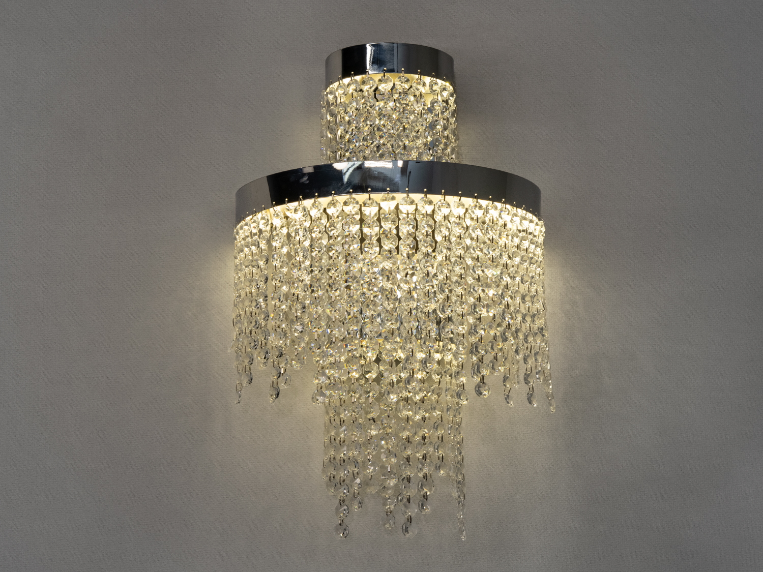 Настінний світильник з кришталевими підвісками, що створюють каскадний ефект. Хромована основа додає сучасного вигляду.