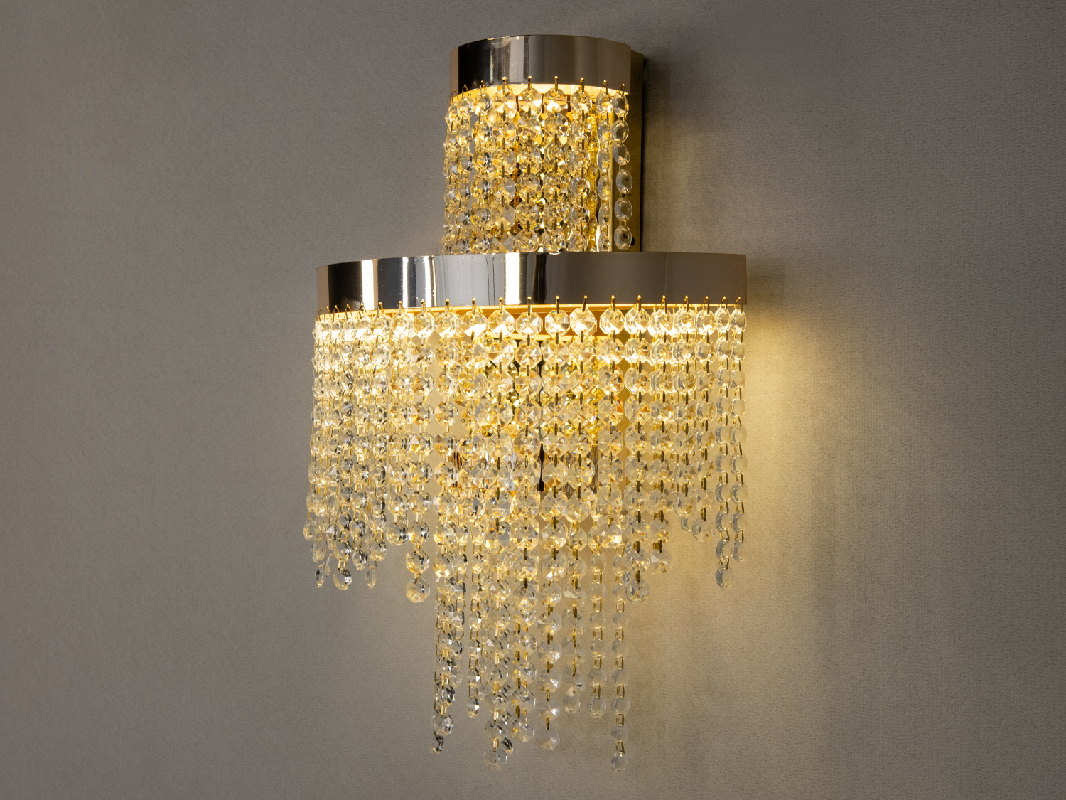 Дворівневий настінний світильник з металевим корпусом і кришталевими елементами, додає елегантності вітальні.