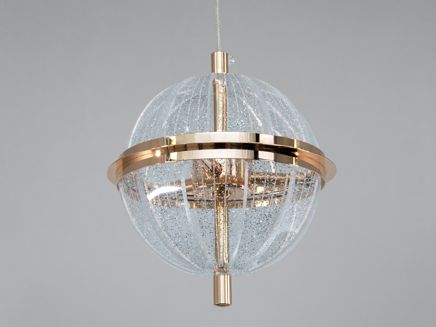 Підвісний світильник з прозорого акрилу, прикрашений металевою смугою, створює ефект розсіяного світла, підходить для вітальні.