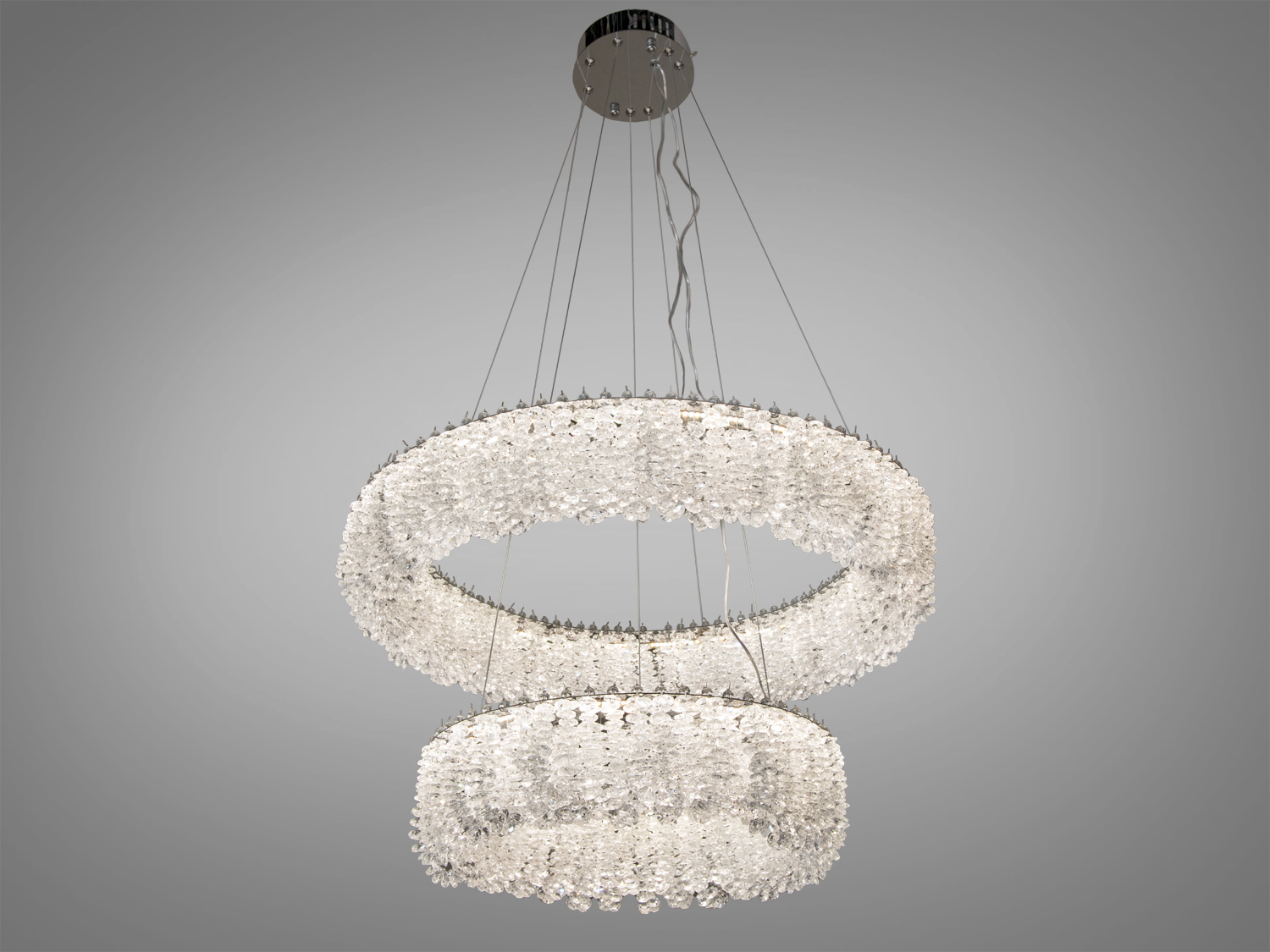 Підвісна люстра з двома кільцями, прикрашена кристалами, що випромінюють нейтральне біле світло. Підходить для вітальні або спальні.