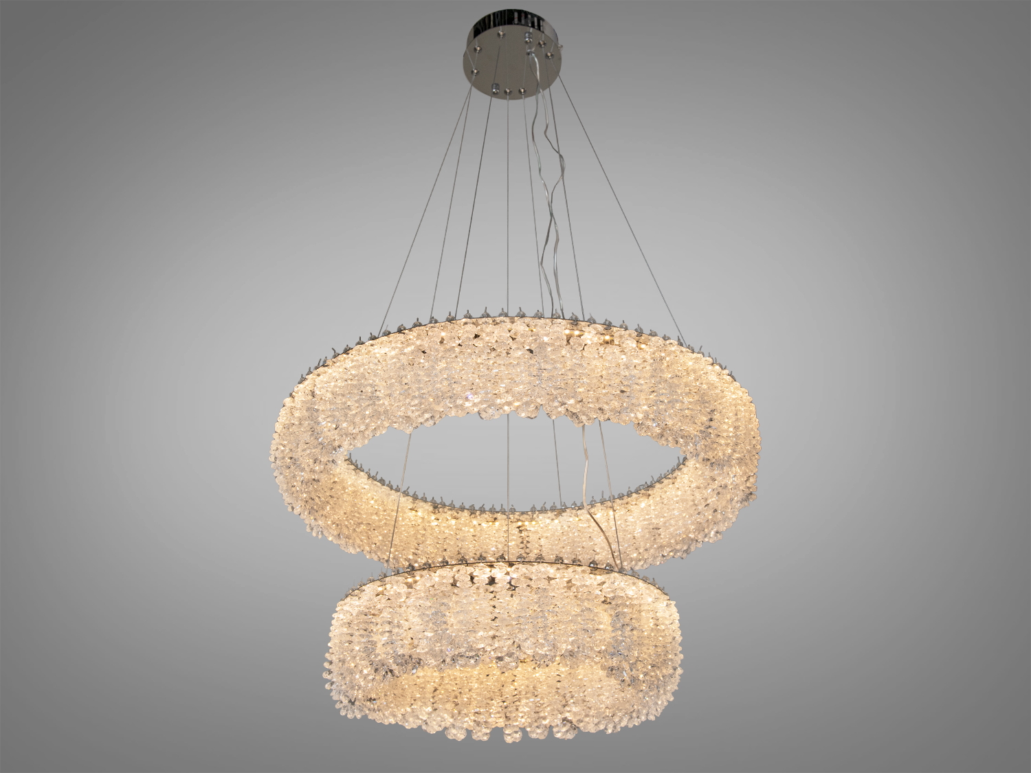 Підвісна люстра з двома кільцями, прикрашена кристалами, що випромінюють тепле біле світло. Ідеальна для затишного інтер′єру.