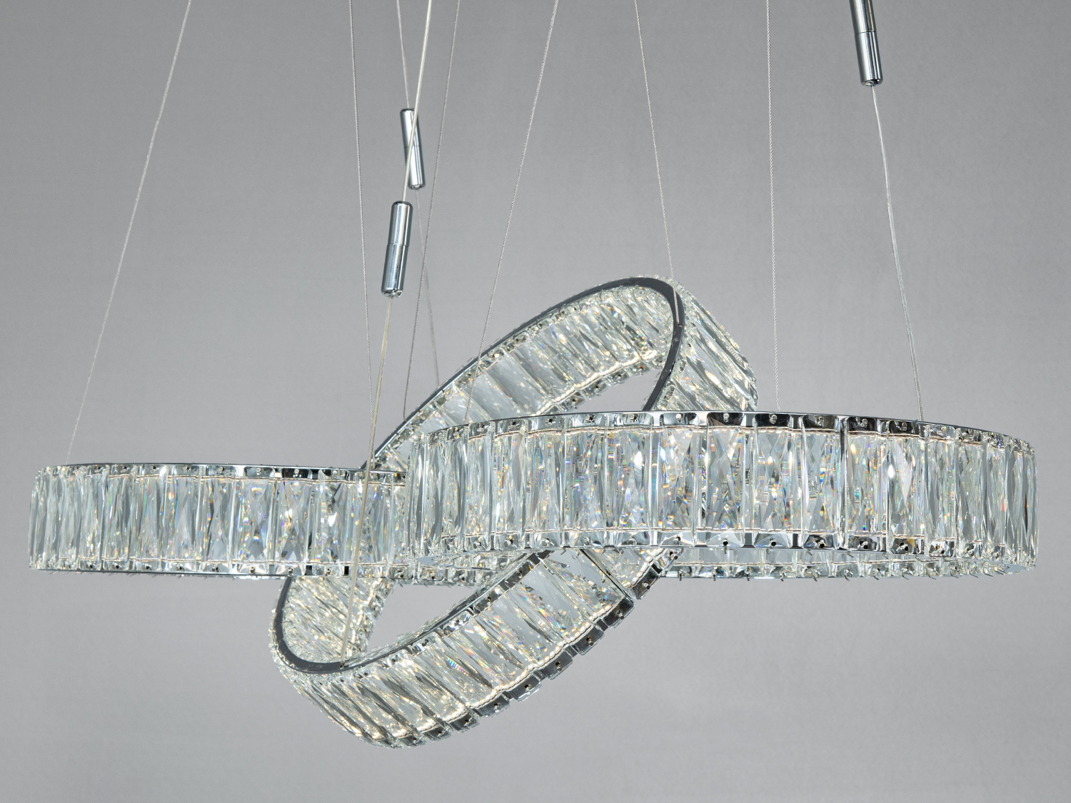 Люстра з трьома переплетеними кільцями, що підвішена на тонких тросах. Кристали забезпечують розкішний блиск у сучасному інтер′єрі.