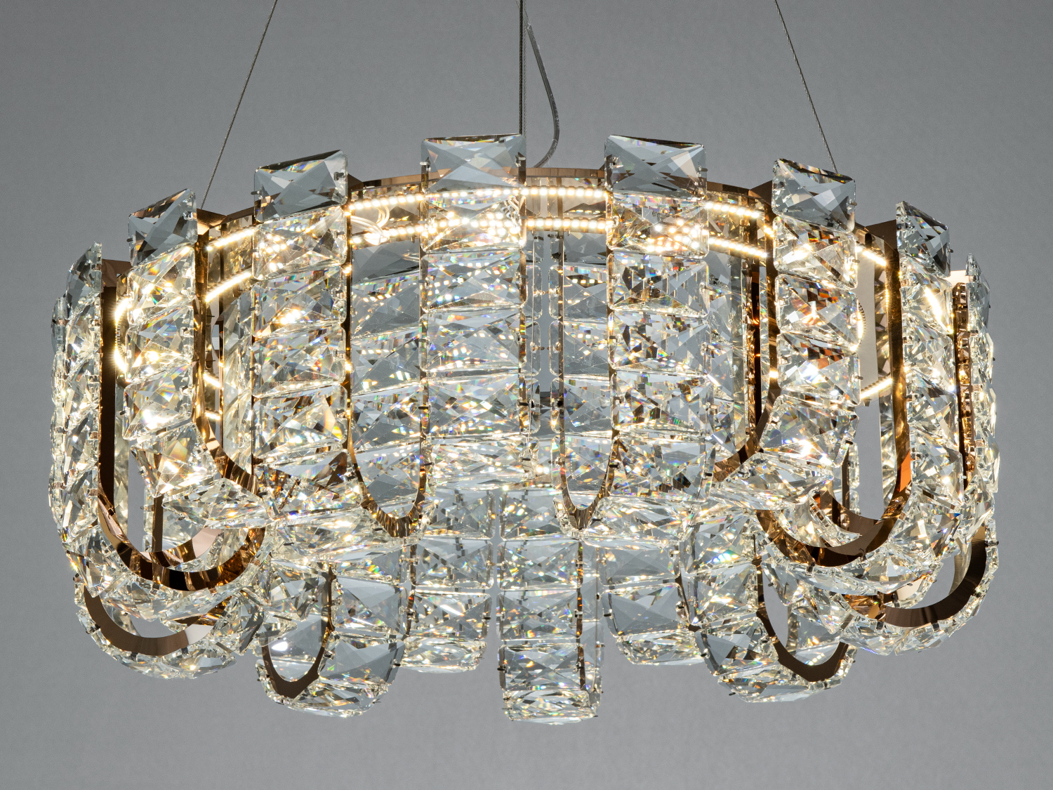 Елегантна люстра з багатошаровими кришталевими деталями, що створює ефектний світловий малюнок.