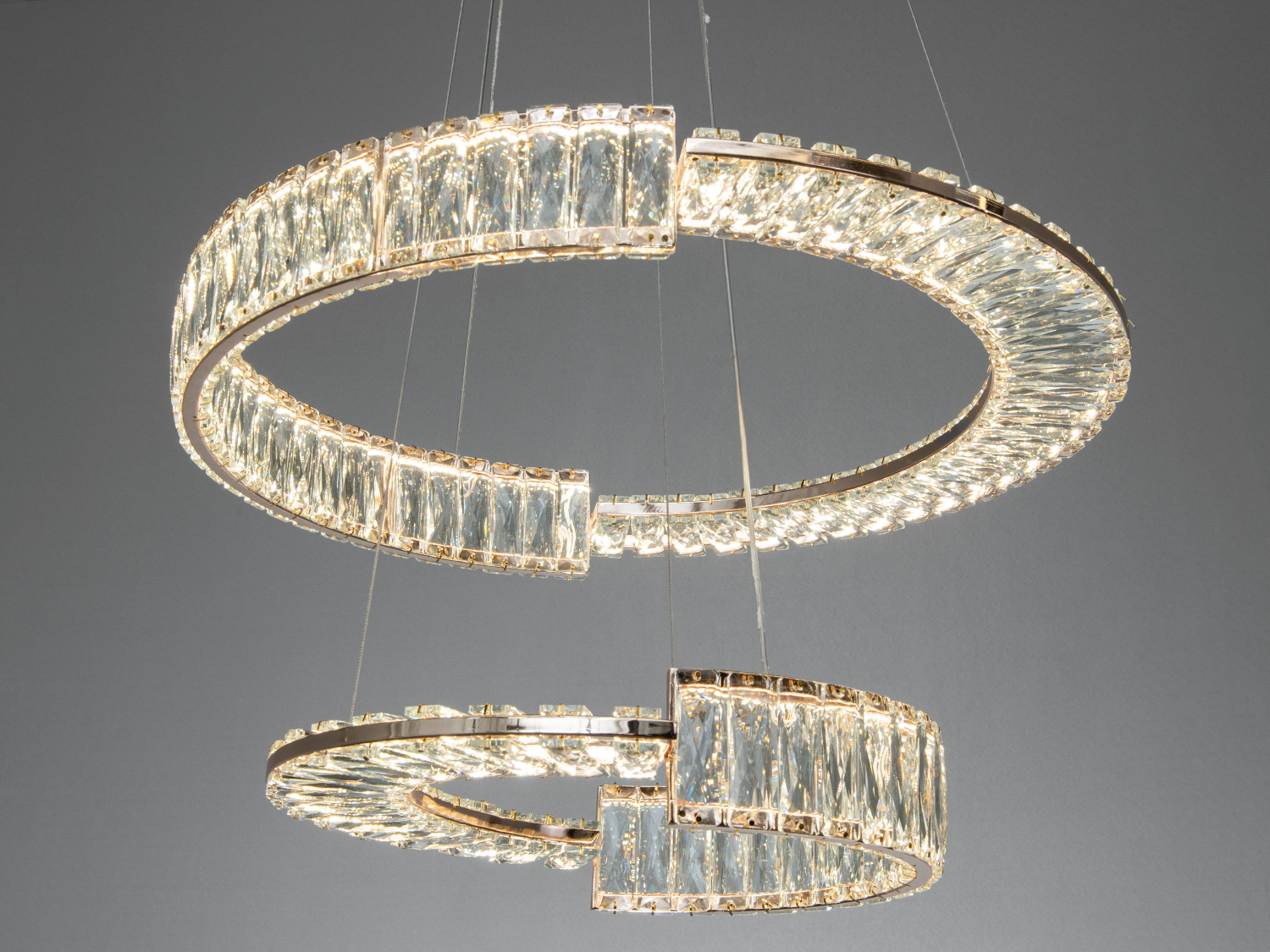 Декоративна люстра з кристалами в сучасному стилі, підвішена на тонких тросах, підходить для вітальні або спальні.