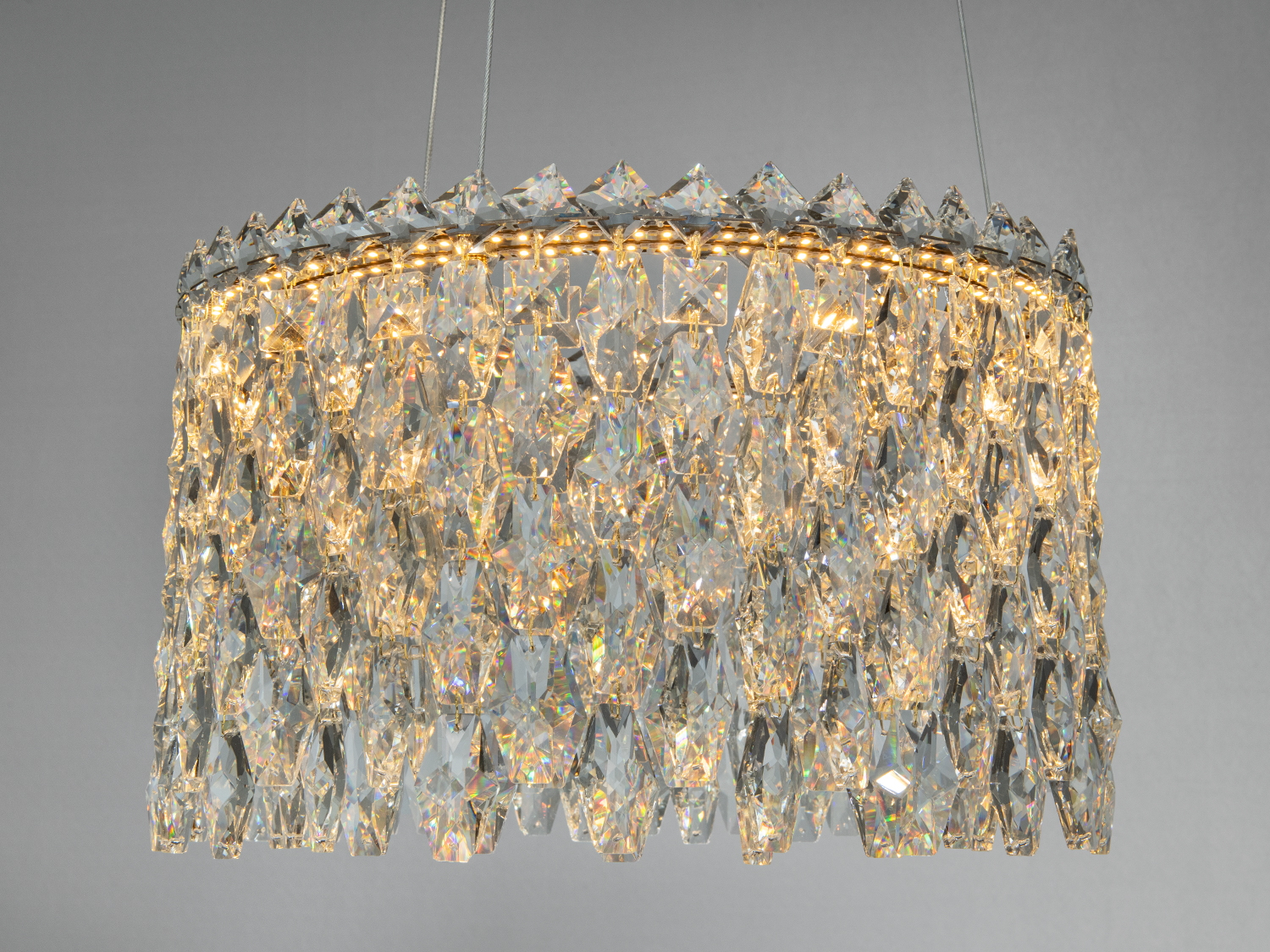 Кругла підвісна люстра з кришталевими підвісками, що відбивають світло. Підходить для вітальні або їдальні.