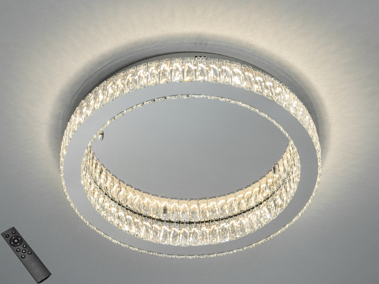 Кругла стельова люстра з кристалами, що відбивають світло, оснащена пультом дистанційного керування для регулювання яскравості.