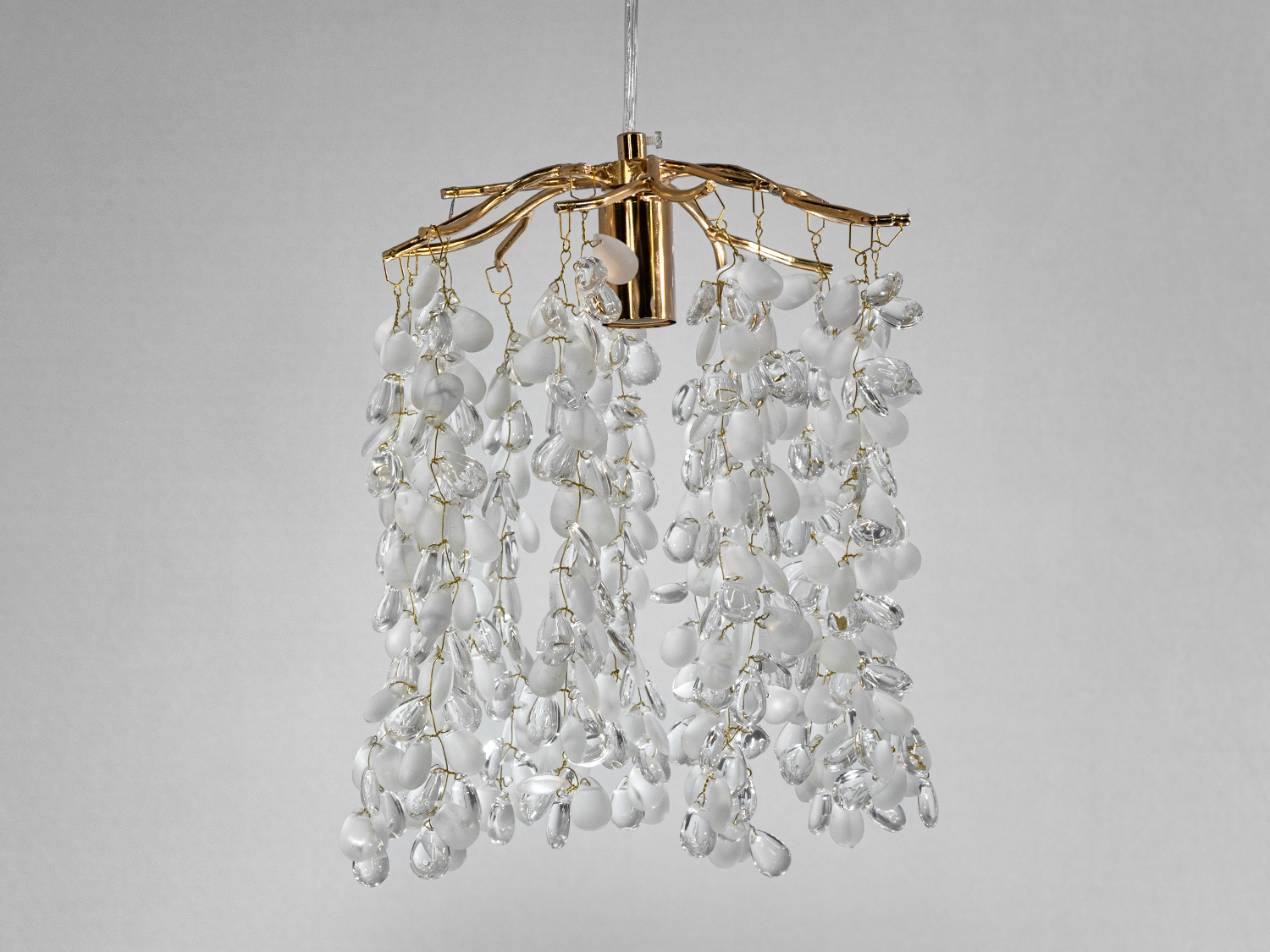 Світильник з золотистою основою і каскадом кришталевих підвісок, які створюють ефект водоспаду, додаючи розкіш в інтер′єр.