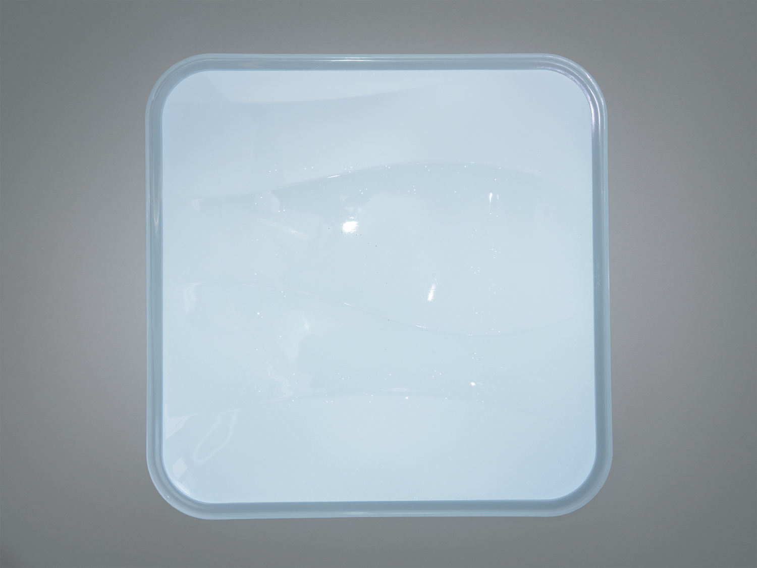 Квадратний світильник з прозорими краями, розроблений для монтажу на стелю, створює м′яке освітлення у приміщенні.