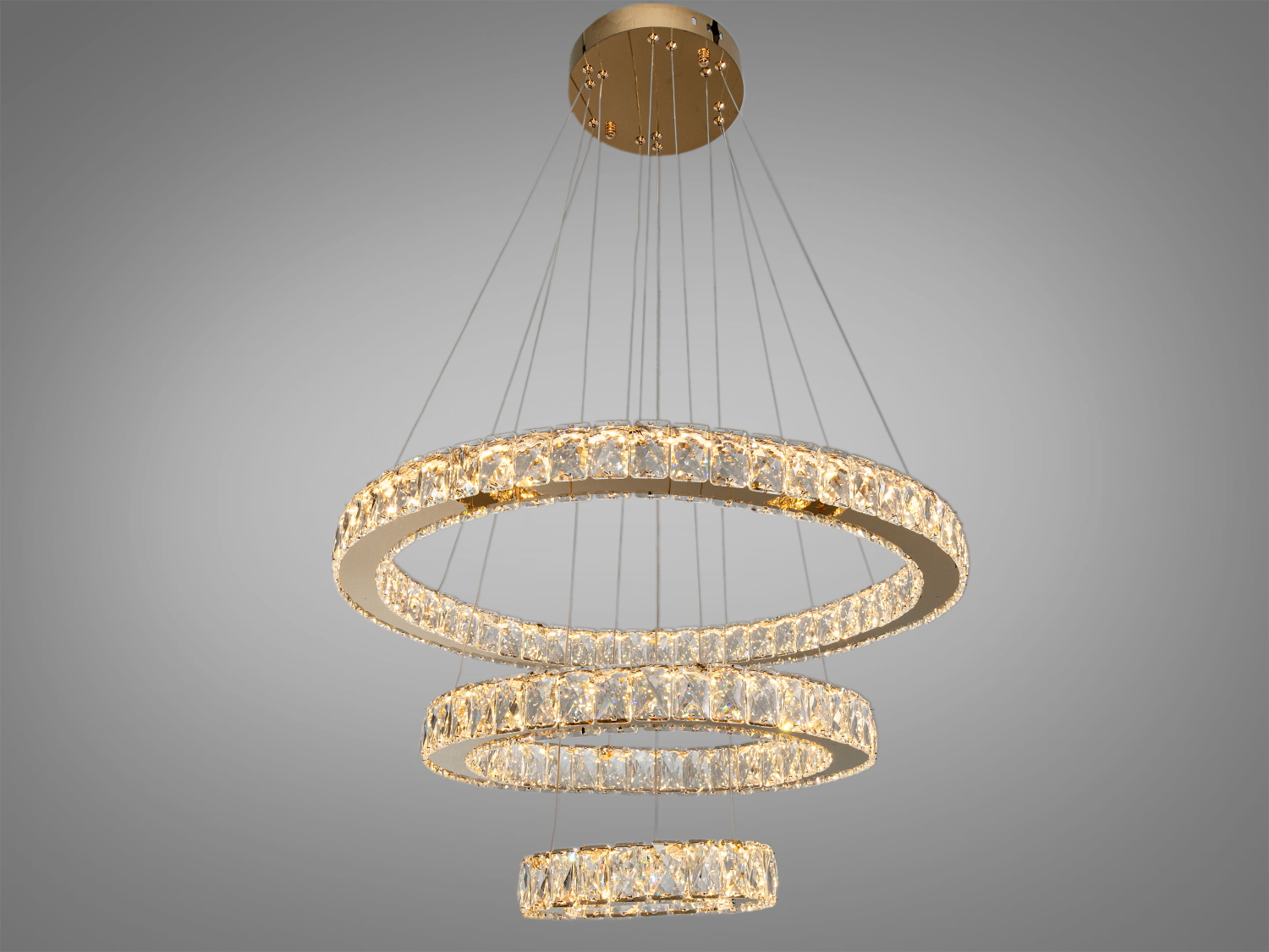 На зображенні представлена розкішна кришталева LED люстра, що складається з трьох концентричних кілець, розміщених на різних рівнях асиметрично.