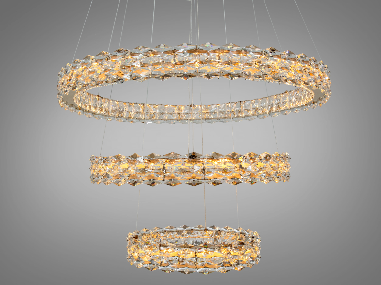 Люстра з трьома кришталевими кільцями, підвішена на тонких дротах, забезпечує рівномірне освітлення та елегантний дизайн.