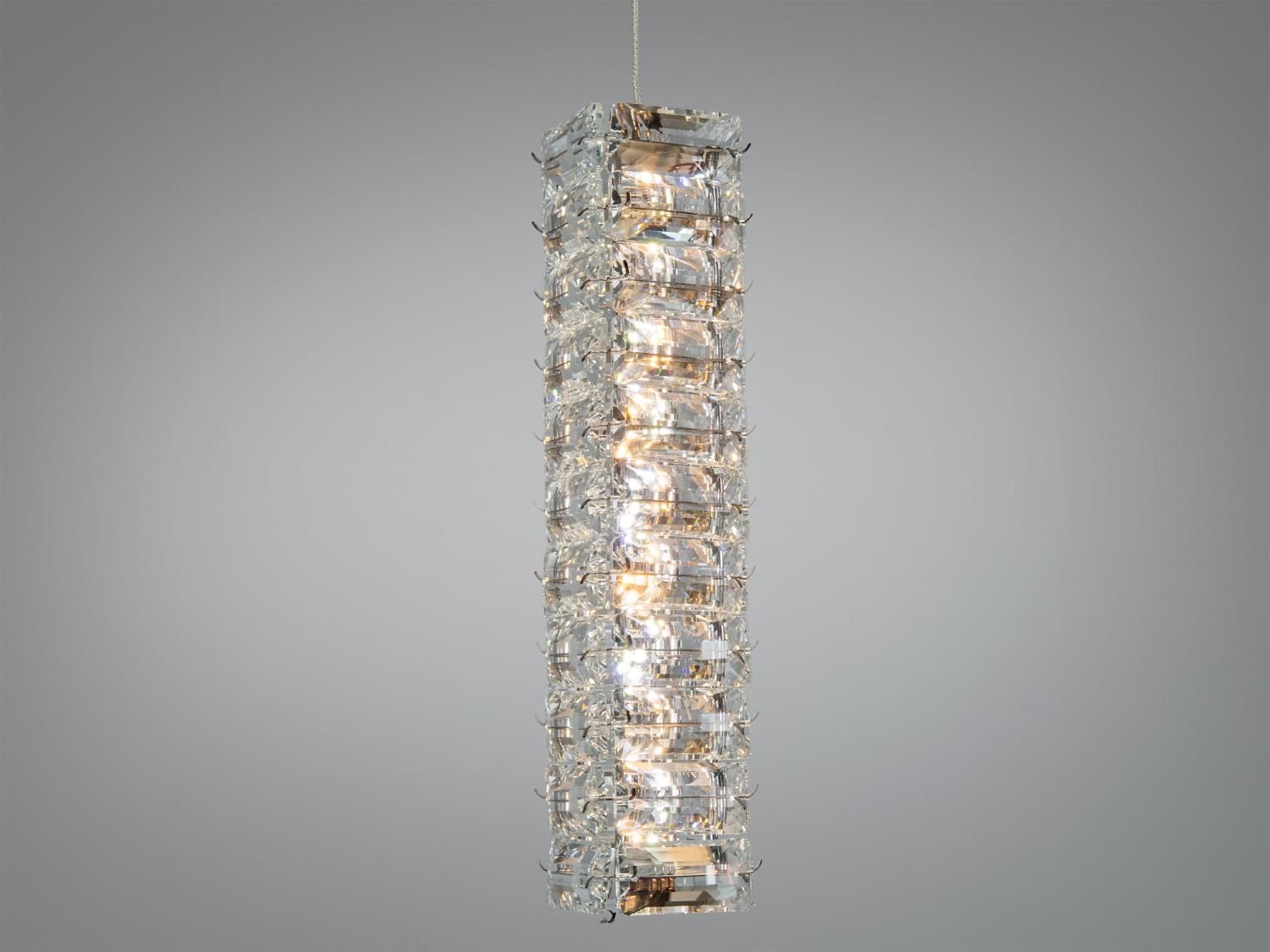 Підвісний світильник з прозорого скла, довгастої форми, з елементами металу, підходить для освітлення обідньої зони.