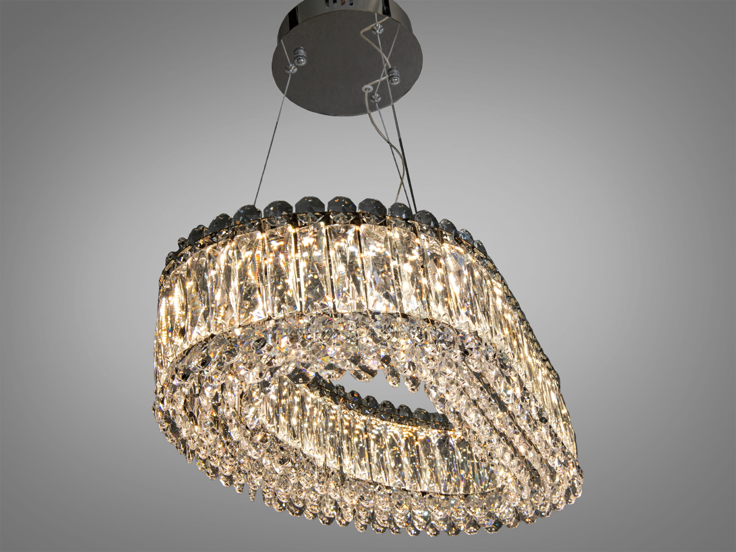 Овальна кришталева люстра з багатошаровим дизайном, підвішена на металевій основі. Підходить для вітальні або їдальні.