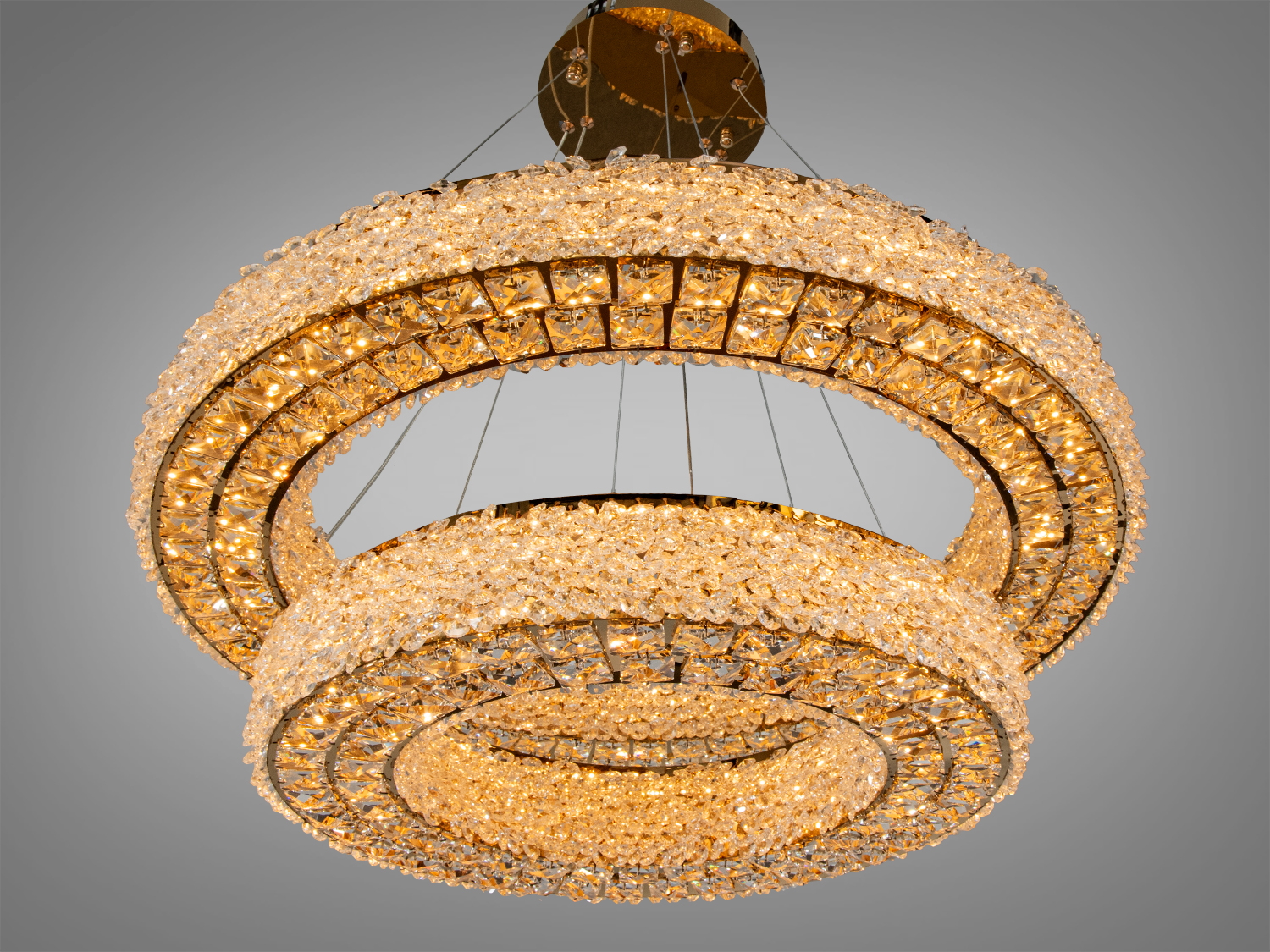 Люстра з теплим жовтим світлом, прикрашена кристалами, підвішена на металевій основі. Підходить для затишних інтер′єрів.