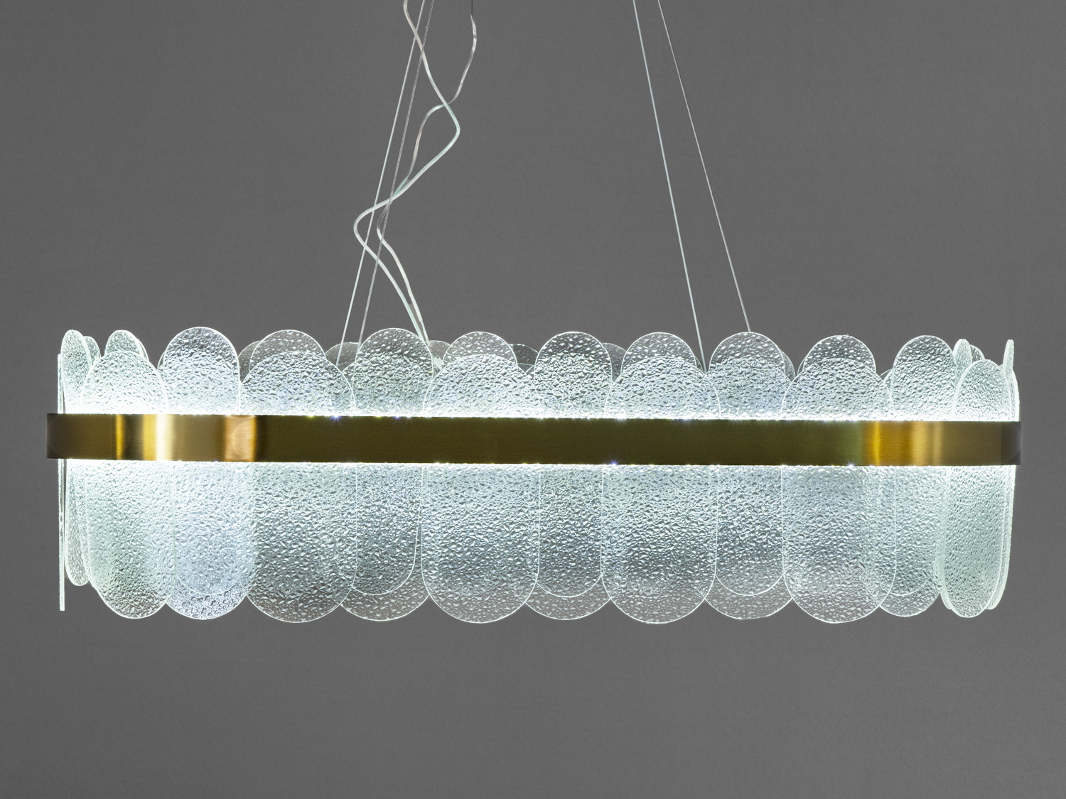 Підвісний світильник з прозорими скляними панелями, що створюють м′яке розсіяне світло. Металевий обідок додає сучасного вигляду.