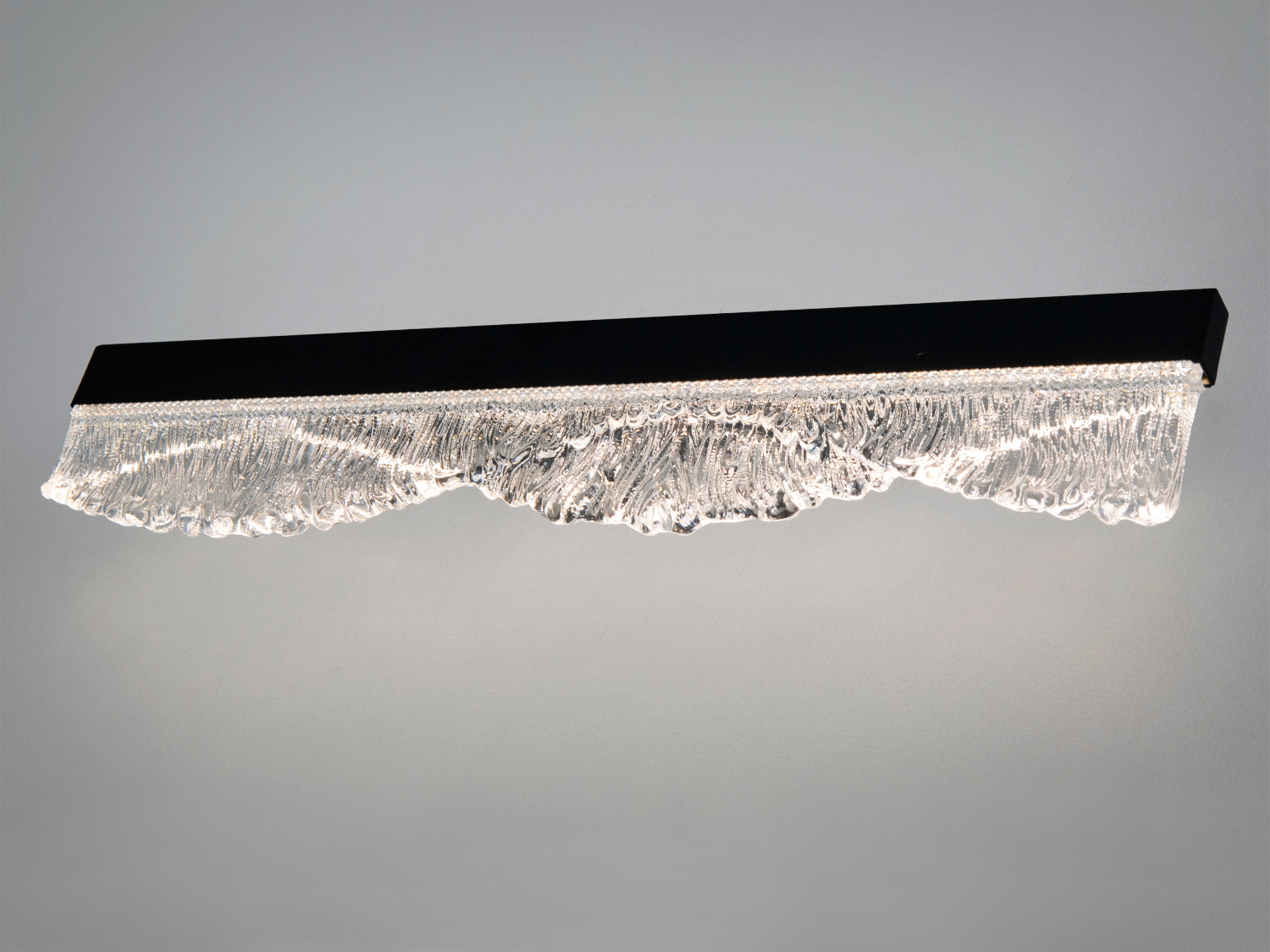 Настінний світильник з прозорим рельєфним склом, що нагадує хвилі, в чорному корпусі. Підходить для сучасного інтер′єру.