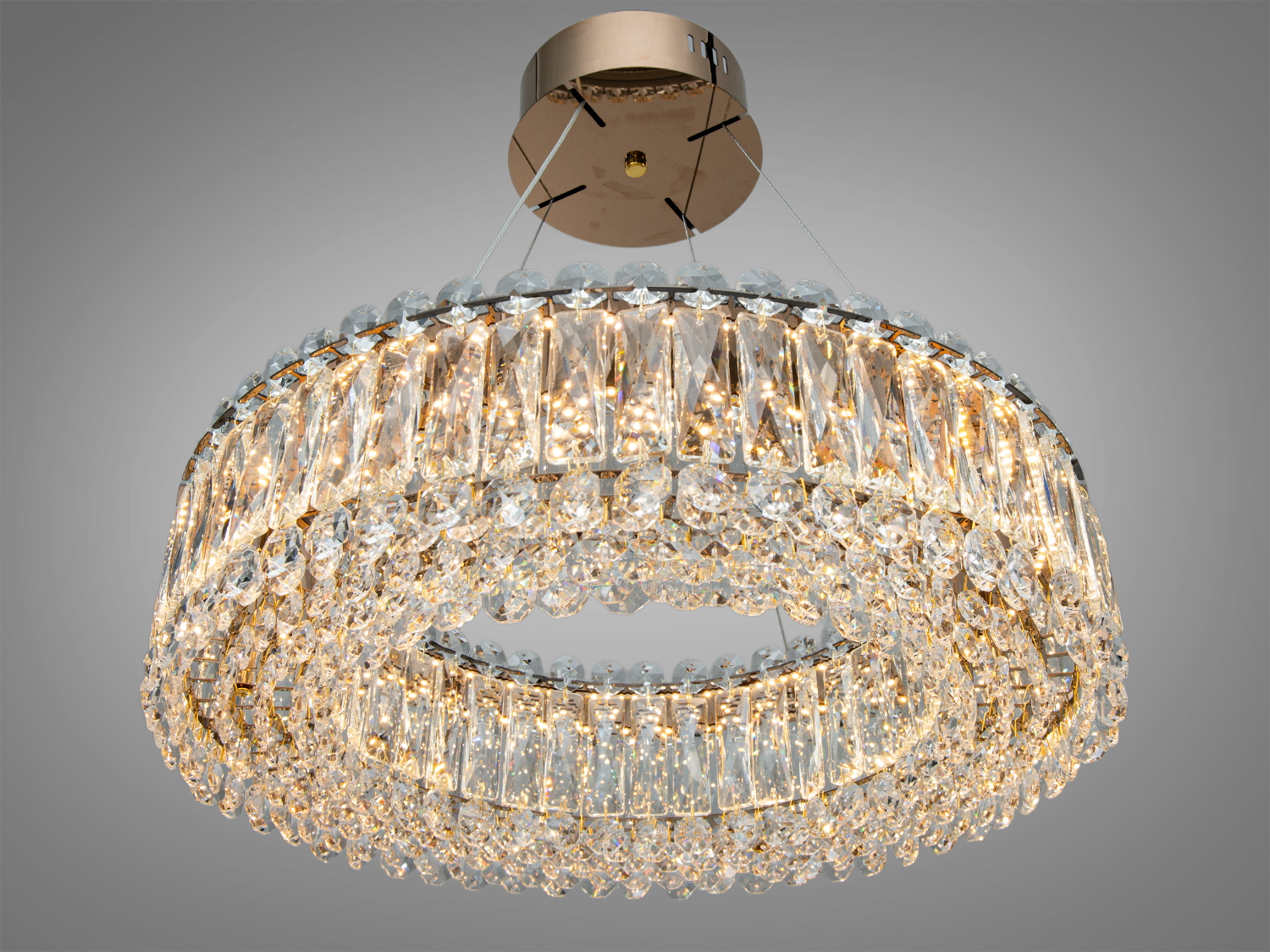 Сучасна кришталева люстра з кільцевими підвісками, що підвішена на тонких дротах. Підходить для високих стель.