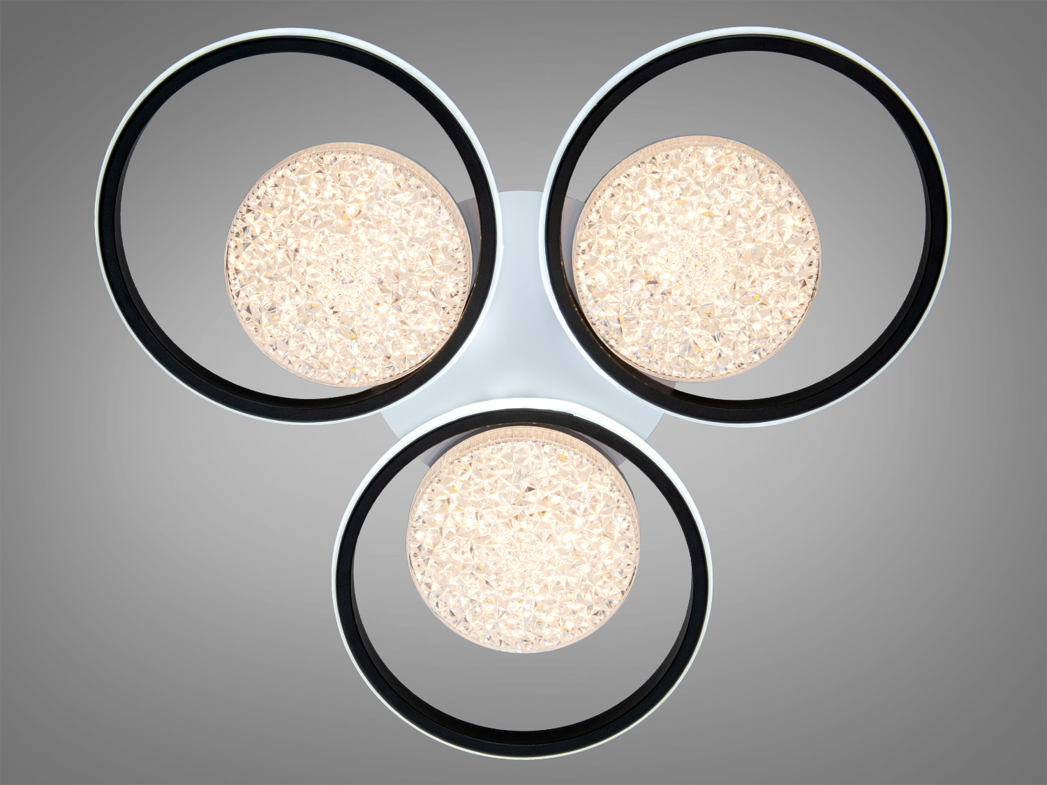 Світильник з трьома кільцями, що випромінюють тепле світло, з кристалічними елементами для затишного освітлення в приміщенні.
