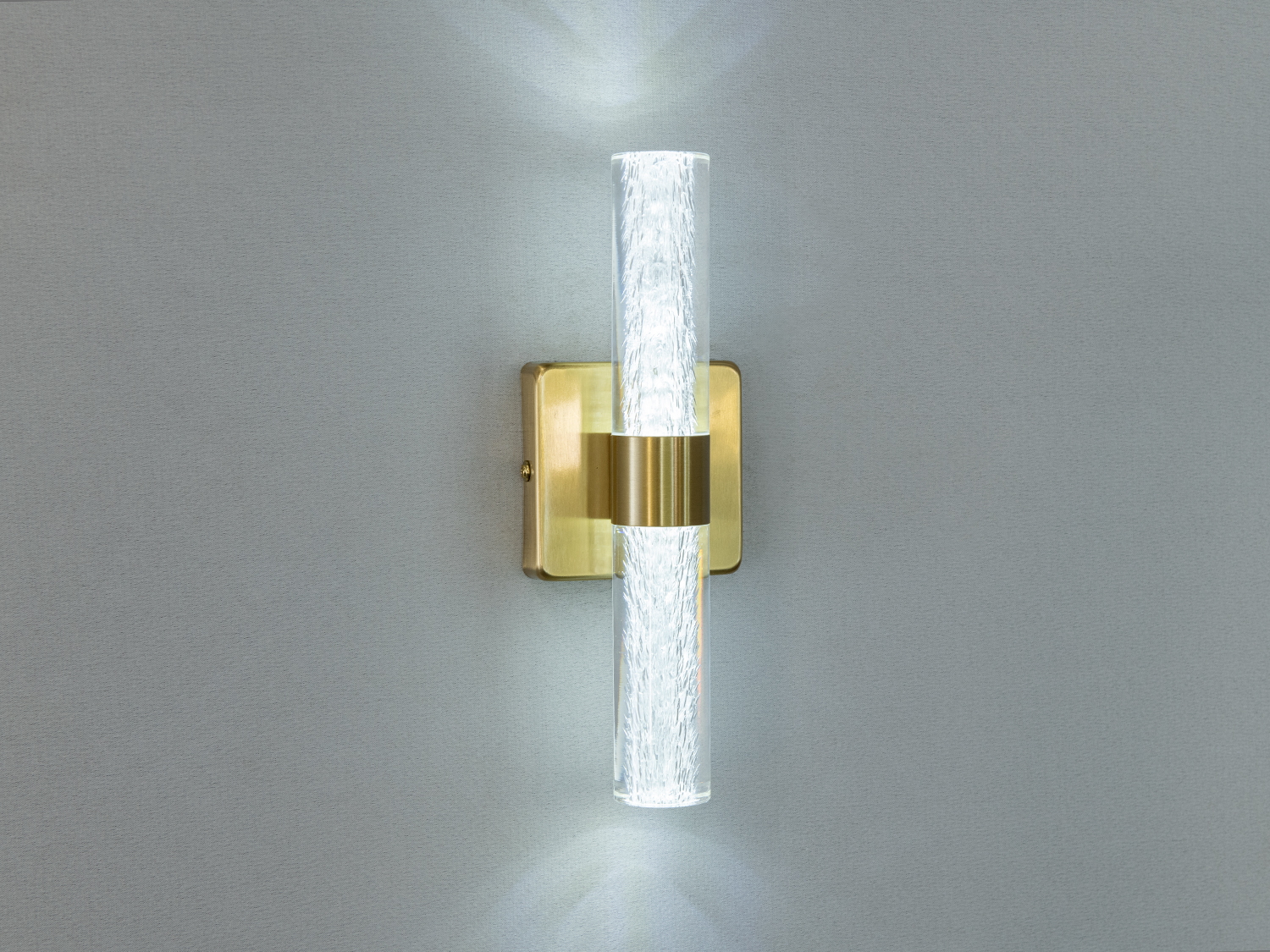 Латунний настінний світильник з вертикальною прозорою трубкою, що створює стильний акцент та рівномірне освітлення.