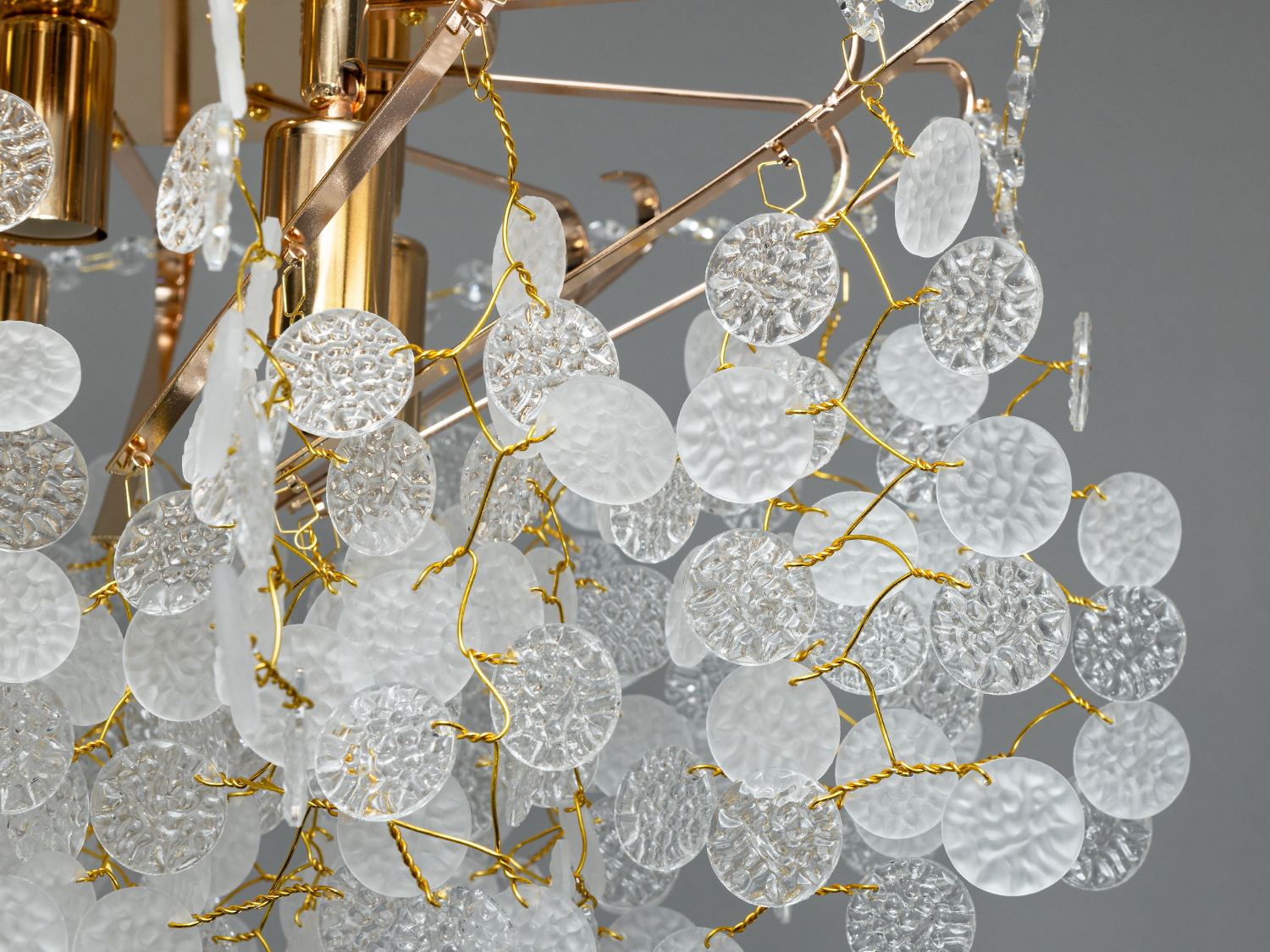 Крупний план люстри з текстурованими кришталевими елементами, підвішеними на золотих дротах, для декоративного освітлення.