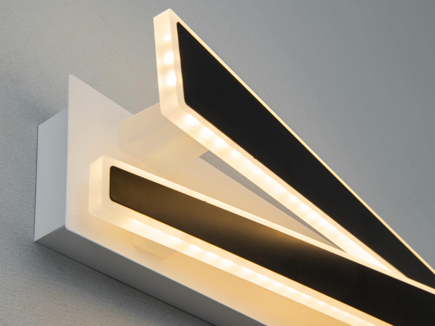 Чорні панелі світильника з теплим жовтим підсвічуванням, що підходять для спальні. Монтаж на стіну.