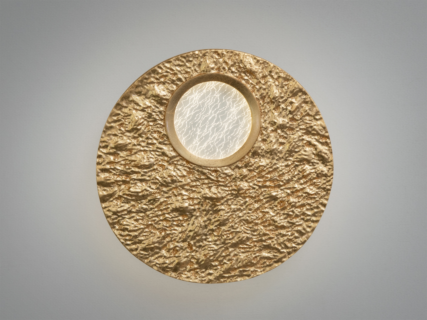 Круглий настінний світильник з текстурованою золотою поверхнею та центральним прозорим елементом. Ідеальний для акцентного освітлення.