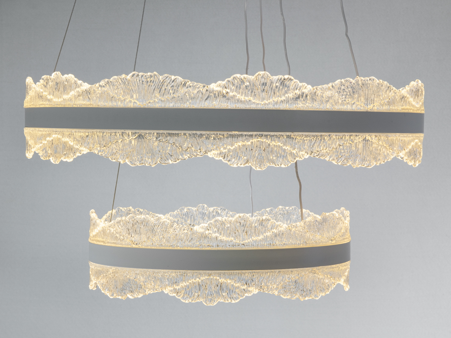 Люстра з ввімкненим теплим світлом, підвішена на тросах, що додає затишку інтер′єру.