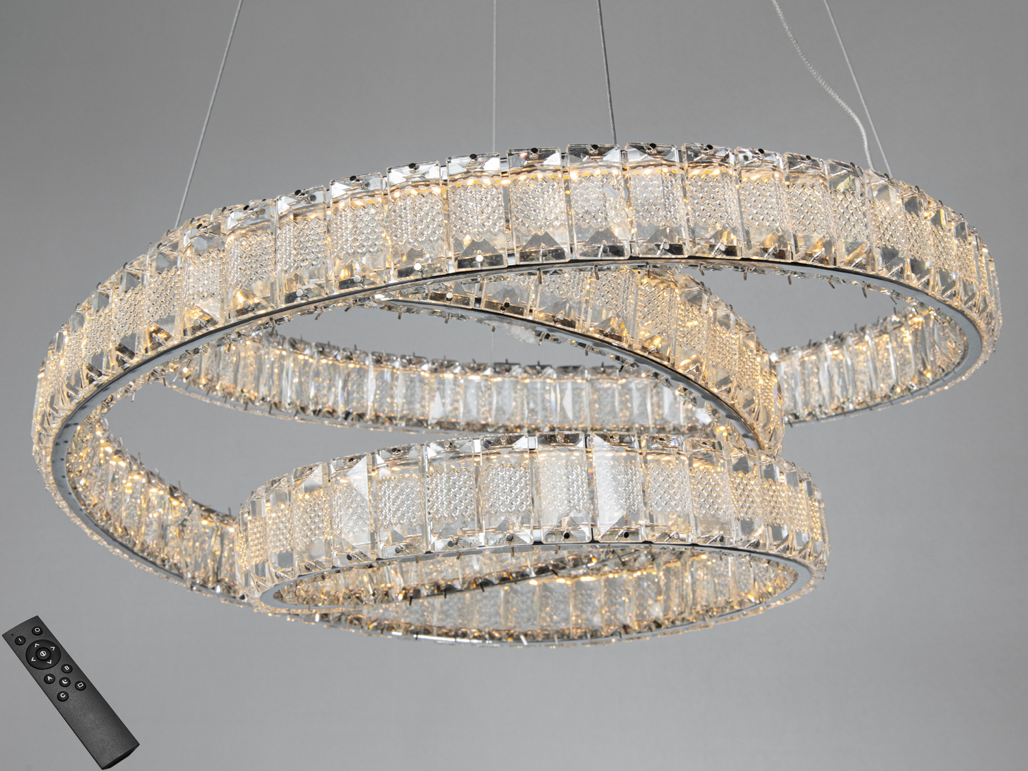 Кругла підвісна люстра з кришталевими елементами, оснащена дистанційним керуванням для регулювання яскравості світла.
