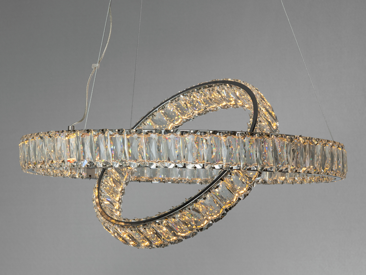 Кришталевий світильник із двома перехресними кільцями, підвішений на металевих тросах, створює ефектний акцент у сучасному інтер′єрі.