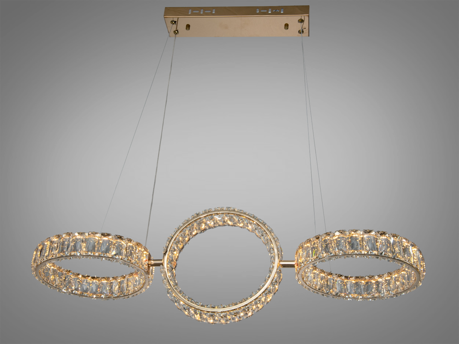 Люстра з трьома кристалічними кільцями на металевому підвісі, що підходить для сучасного інтер′єру.