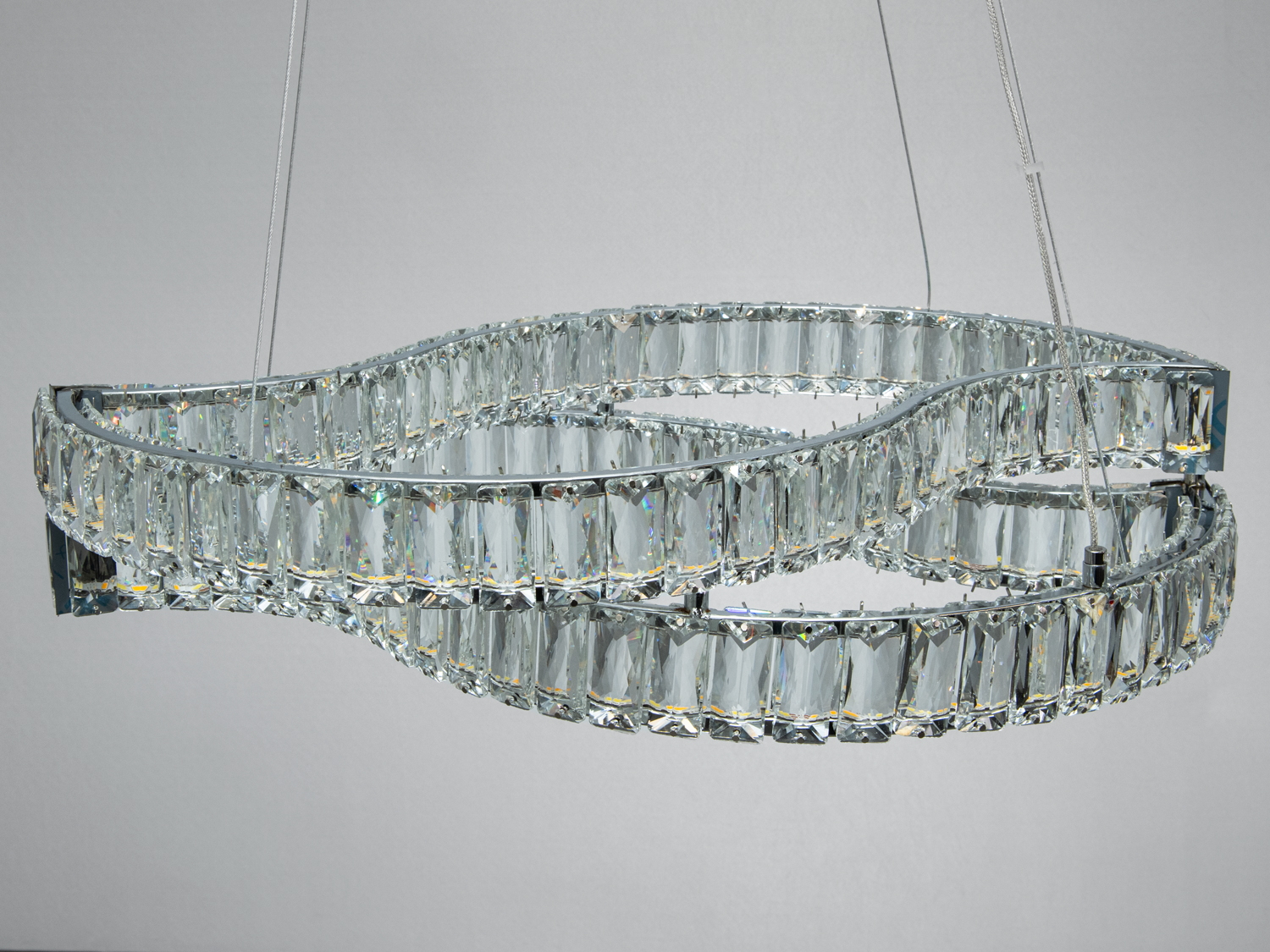 Люстра з кришталевими вставками, що формують плавні лінії, підвішена на тонких тросах, ідеально підходить для вітальні.