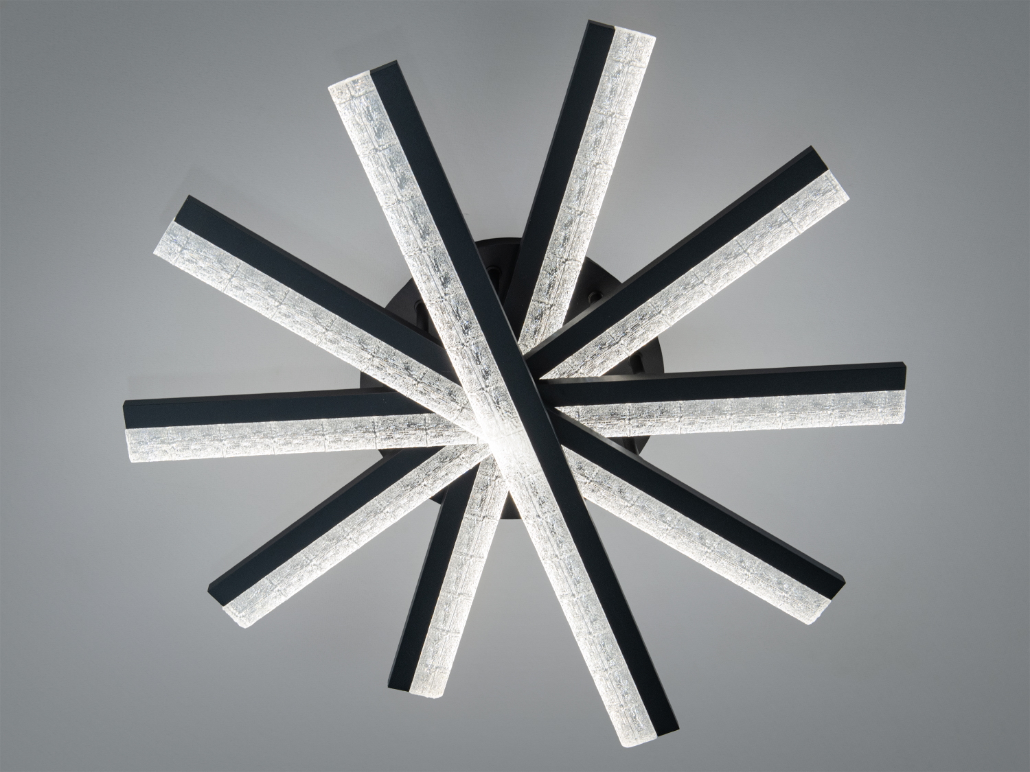 Світильник у формі зірки з чорними променями та прозорими вставками, що створюють м′яке розсіяне світло. Підходить для сучасних інтер′єрів.