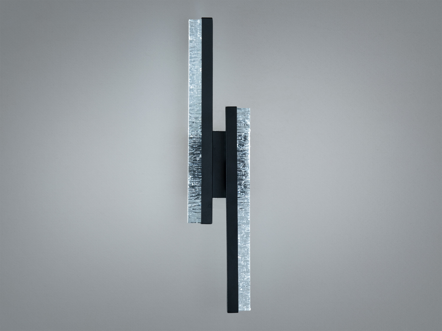 Вертикальний настінний світильник з чорного металу, оснащений скляними елементами, забезпечує рівномірне освітлення.