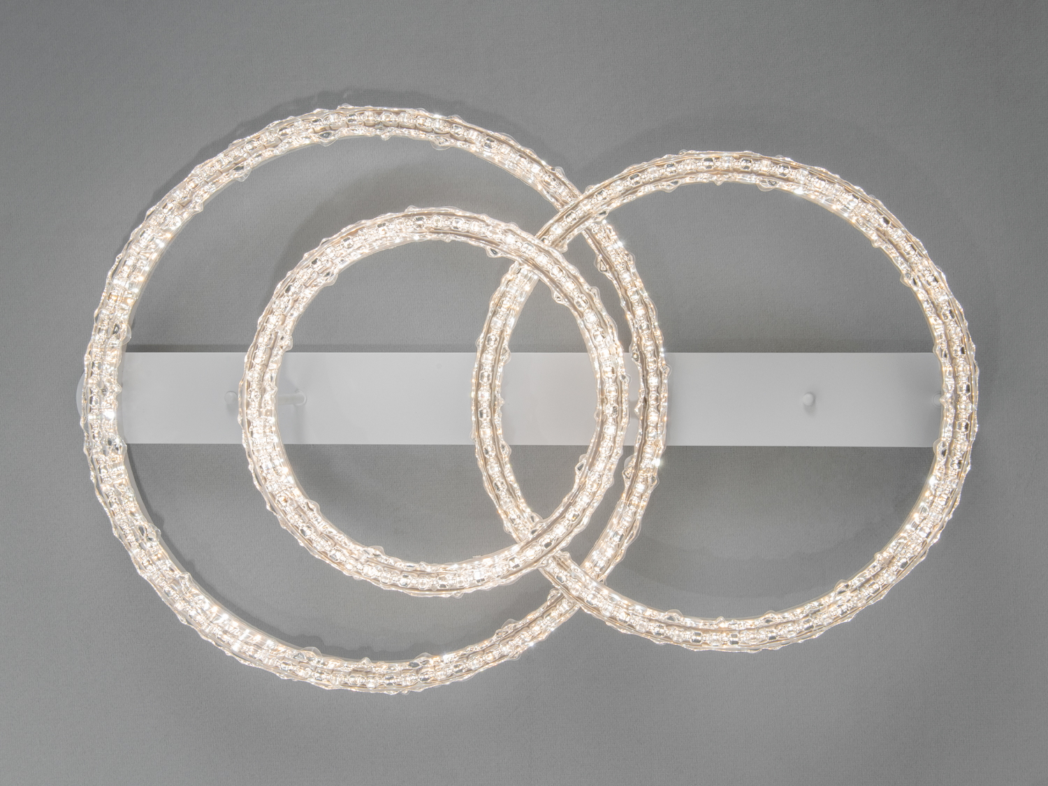 Світильник з трьома кільцями, закріплений на прямокутній основі. Призначений для монтажу на стелю, підходить для сучасних інтер′єрів.