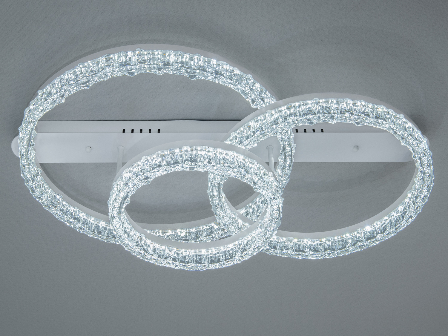 Стельовий світильник з трьома переплетеними кільцями. Виконаний з прозорого матеріалу, що створює ефектний світловий акцент.