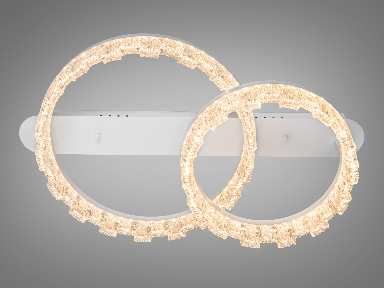 Настінний світильник з двома кільцями, що випромінюють тепле жовте світло. Виготовлений з прозорого матеріалу, ідеальний для затишних приміщень.