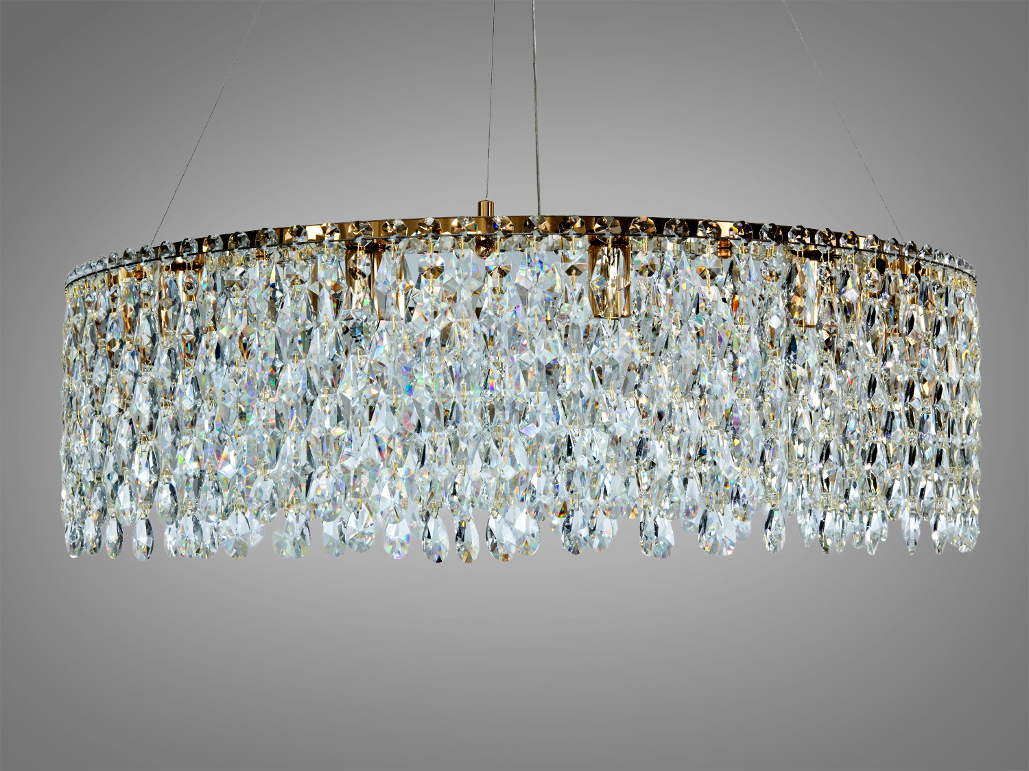 Кругла  золота люстра з кришталевими підвісками, що підвішена на тонких тросах. Ідеальна для сучасного інтер′єру.