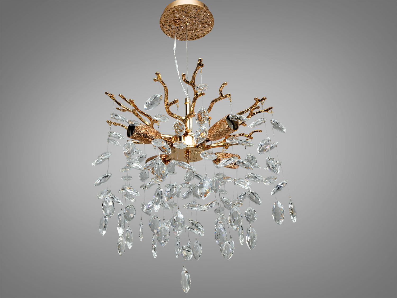 Люстра з кришталевими підвісками на золотистій основі, що має форму розгалужених гілок, створює елегантний світловий ефект.