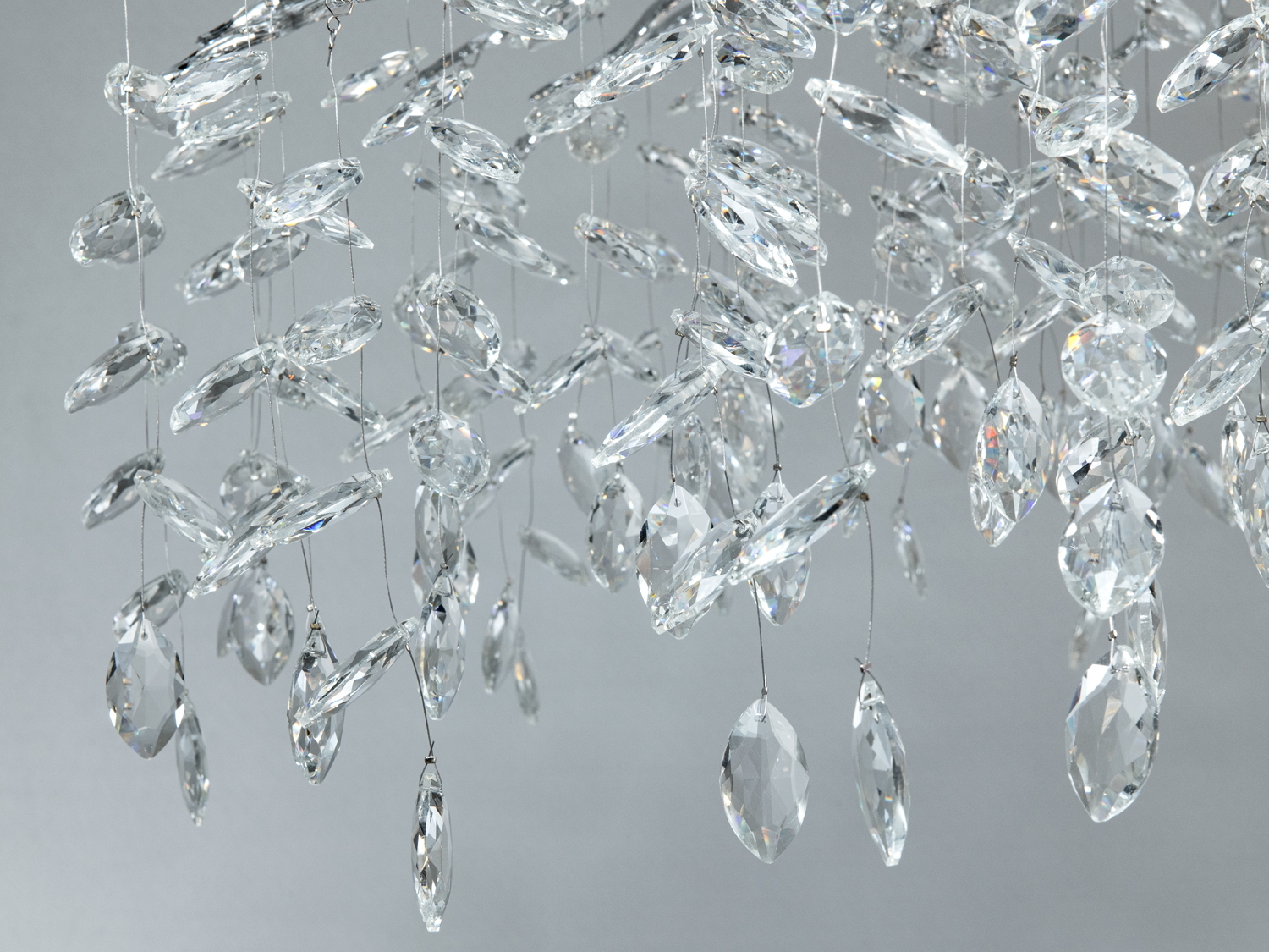 Деталі кришталевого світильника з підвісками, що нагадують краплі дощу. Підходить для елегантного декору.