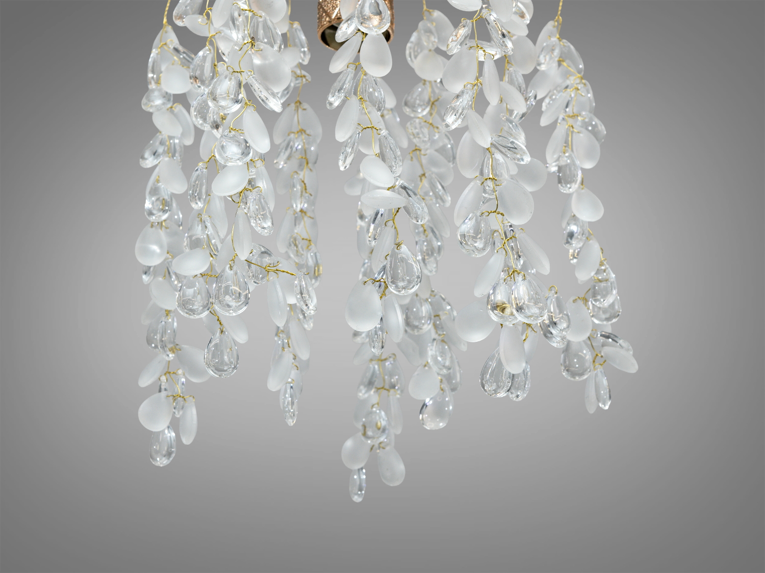 Деталь кришталевої люстри з підвісками, що нагадують краплі роси, на золотистих нитках, підходить для елегантного освітлення.