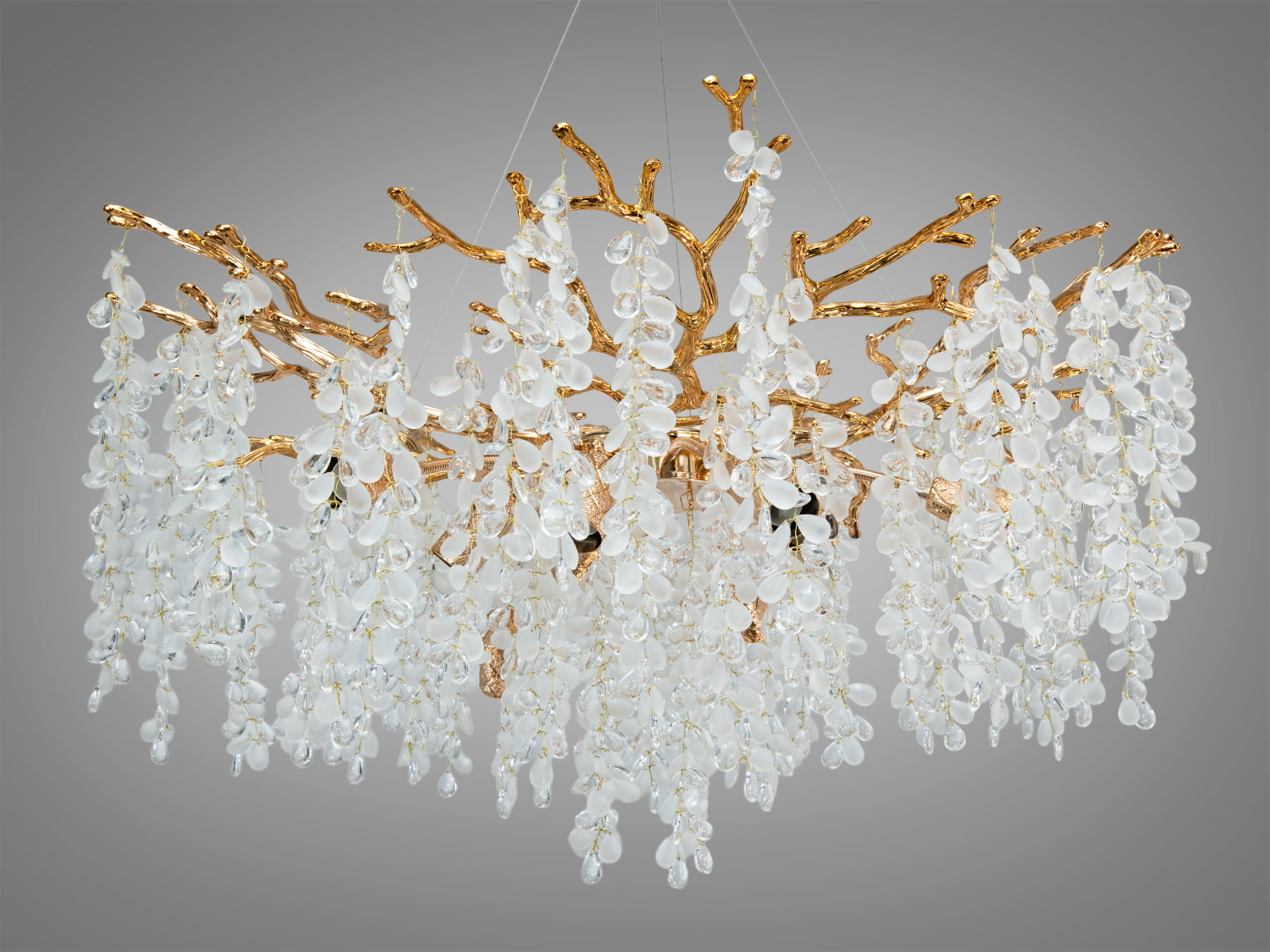 Підвісна люстра з гіллястим дизайном, прикрашена кришталевими підвісками у формі крапель, створює ефект водоспаду в інтер′єрі.