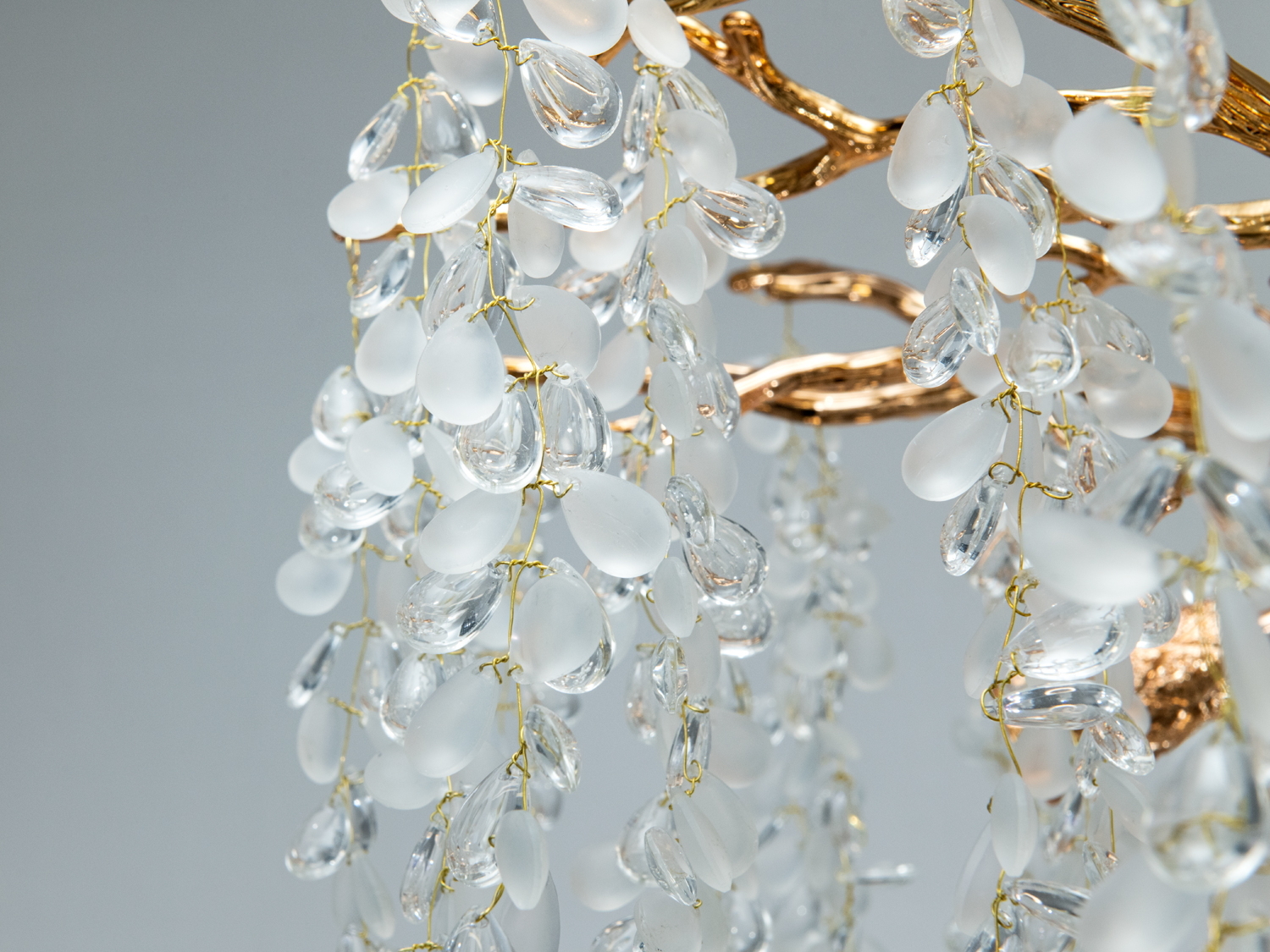 Детальне зображення скляних підвісок люстри, що підвішені на золотистих нитках, підкреслює їхню прозорість і витонченість.
