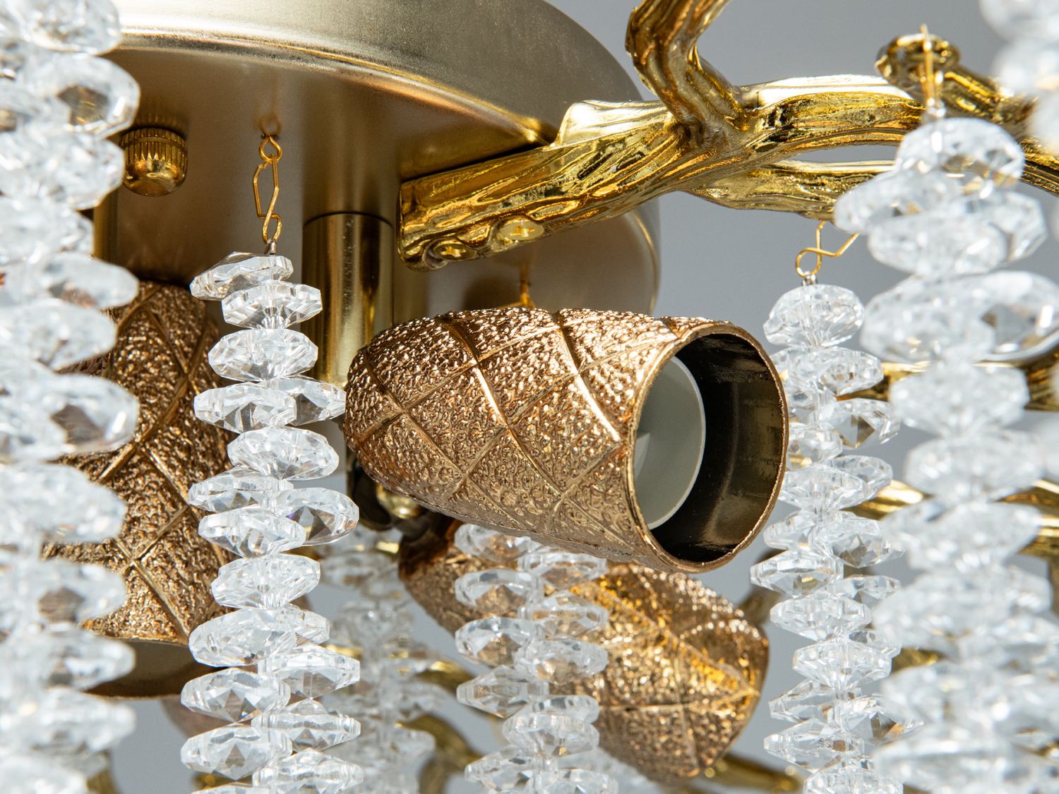 Деталь люстри з текстурованими бронзовими патронами та прозорими кришталевими підвісками. Підходить для елегантного освітлення.