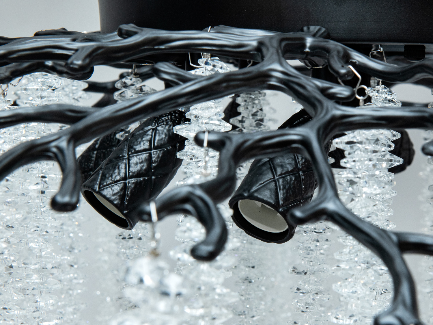 Деталь чорного каркаса люстри з текстурованими елементами та кришталевими підвісками, що підкреслює її унікальний дизайн.